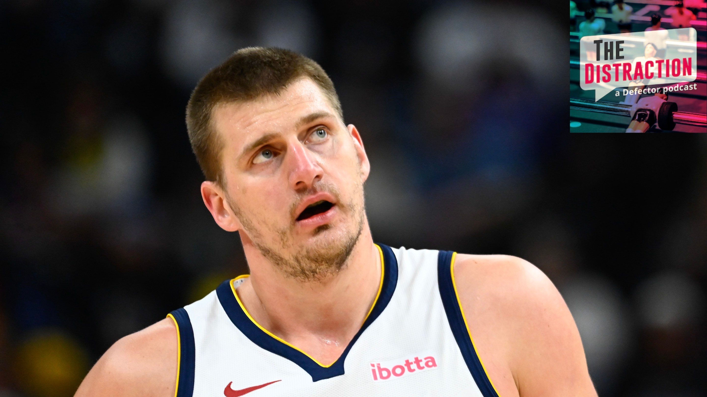 Nikola Jokic #15 of the Denver Nuggets looks on during the first half against the Utah Jazz at Delta Center on April 9, 2024. I put the little Distraction logo at upper right so it looks like he's glowering at it.