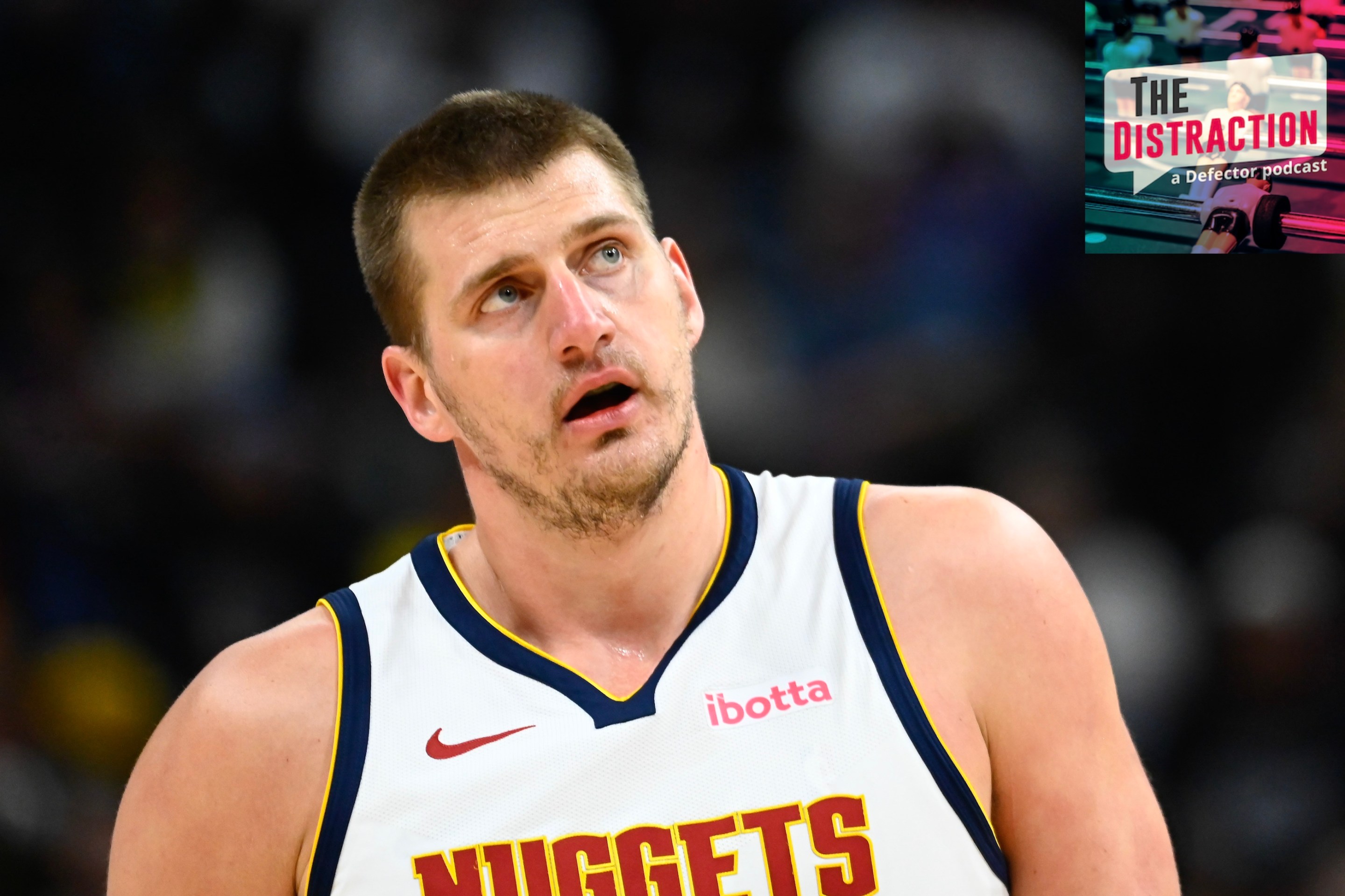 Nikola Jokic #15 of the Denver Nuggets looks on during the first half against the Utah Jazz at Delta Center on April 9, 2024. I put the little Distraction logo at upper right so it looks like he's glowering at it.