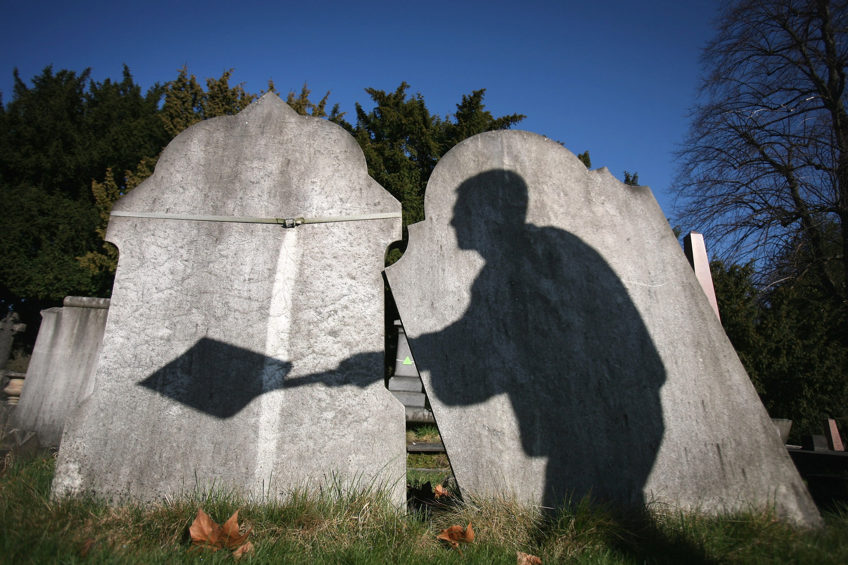 LONDON, ENGLAND - MARCH 02: The shadow of a cemetery worker is cast on reclaimed gravestones in London City Cemetery on March 2, 2009 in London, England. The cemetery is piloting a scheme whereby graves over 75 years old become eligible for reclamation. New interments will be placed into the existing graves, the headstones will be turned around and re-used, carving the names of the newly deceased. Once a grave has been earmarked by English heritage the cemetery must wait one year to see if family members claim the existing grave. By conserving as many memorials as possible the City of London hopes to maintain the historic cemetery landscape and sustain buriel provisions for the future. (Photo by Dan Kitwood/Getty Images)