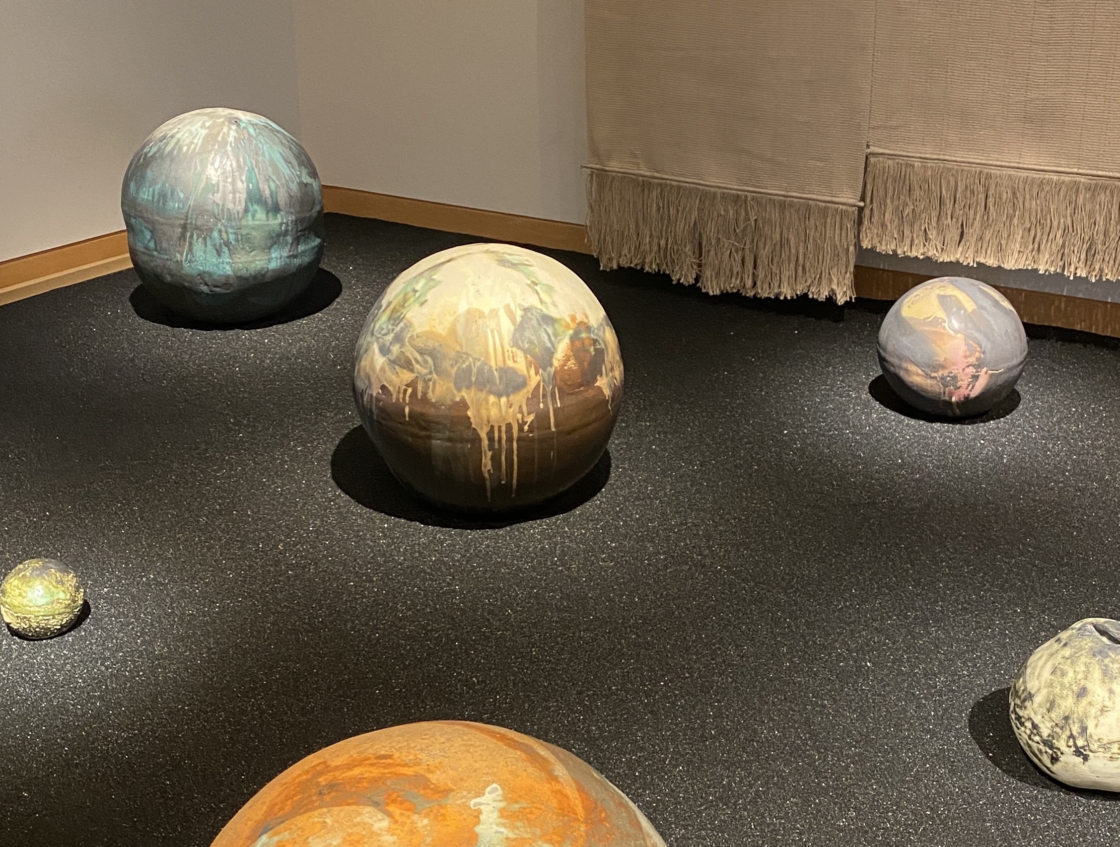 several of Toshiko Takaezu's moon-shaped ceramics on black sand