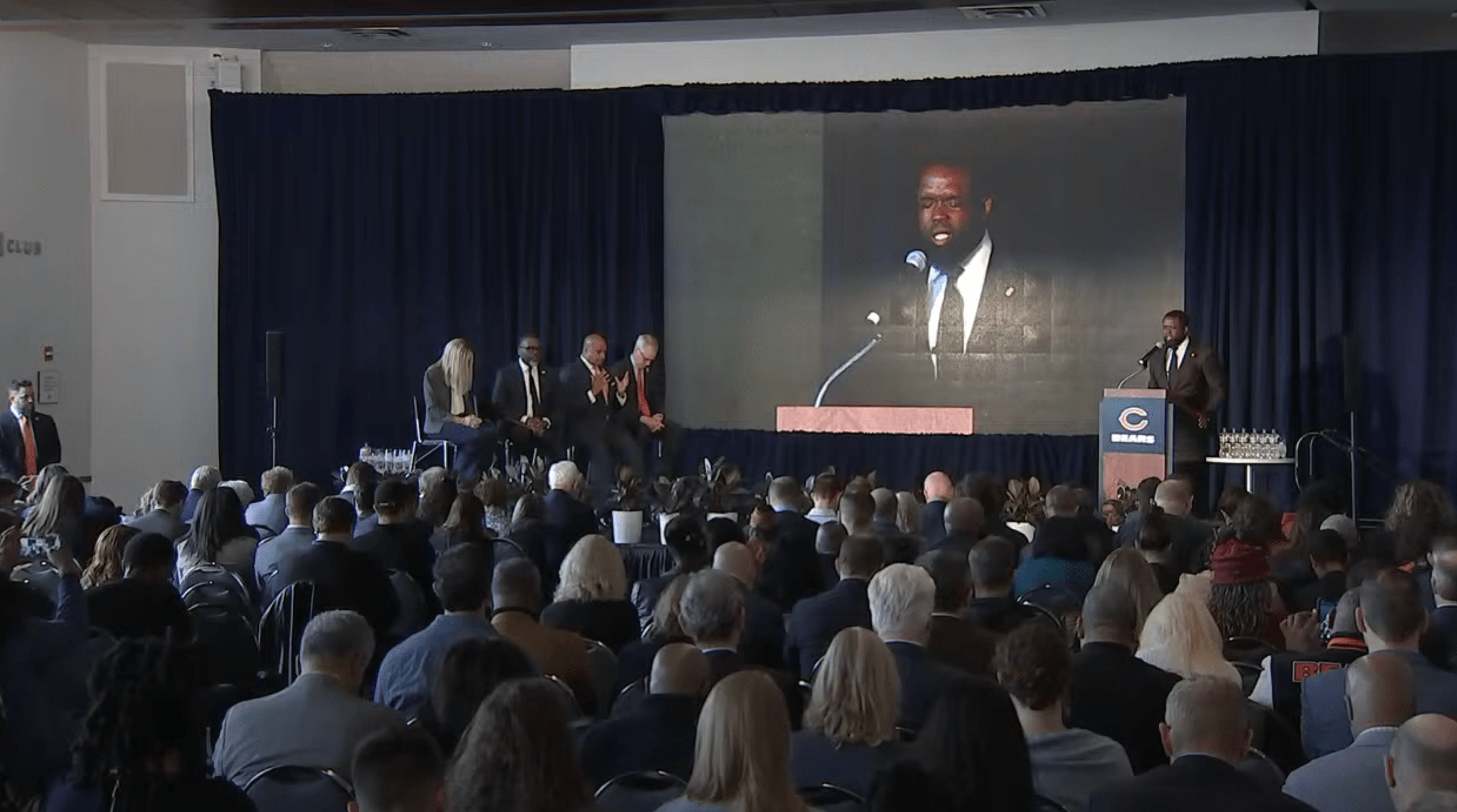 Dr. Charles E. Dates leads the room in prayer before the stadium presentation.