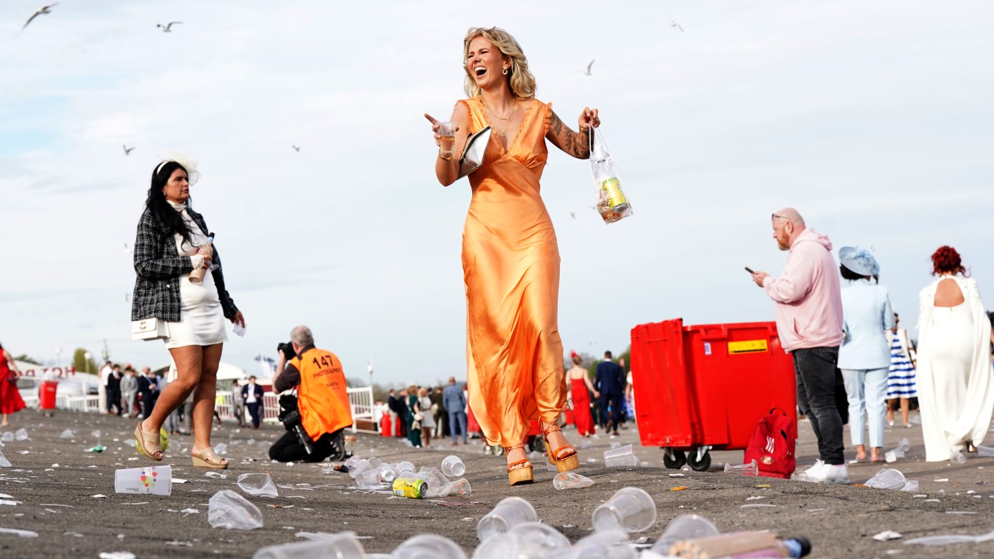 A racegoer stands tall among the trash, alcohol in hand, at the end of day two of the 2024 Randox Grand National Festival at Aintree Racecourse, Liverpool.