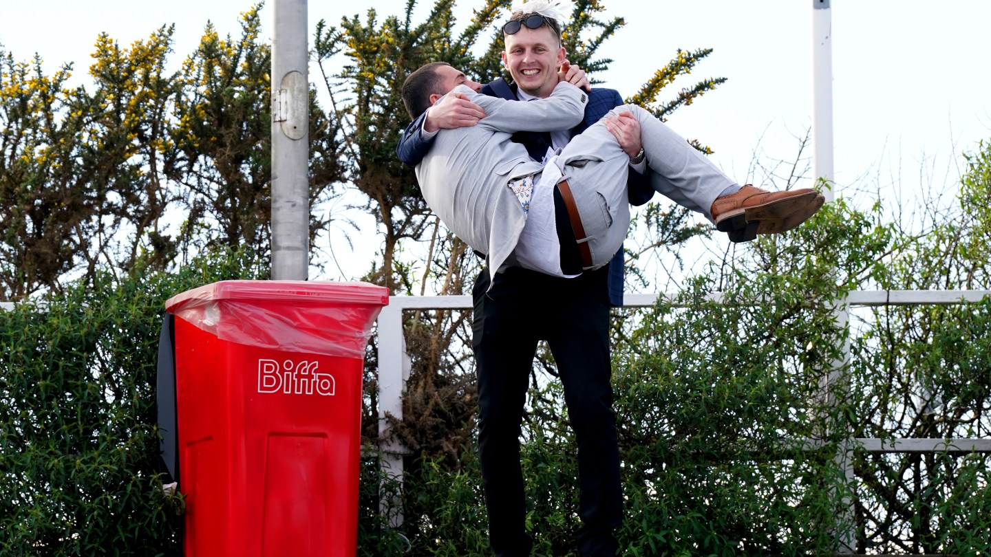 Racegoers in front of a trash can at the end of day two of the 2024 Randox Grand National Festival at Aintree Racecourse, Liverpool.