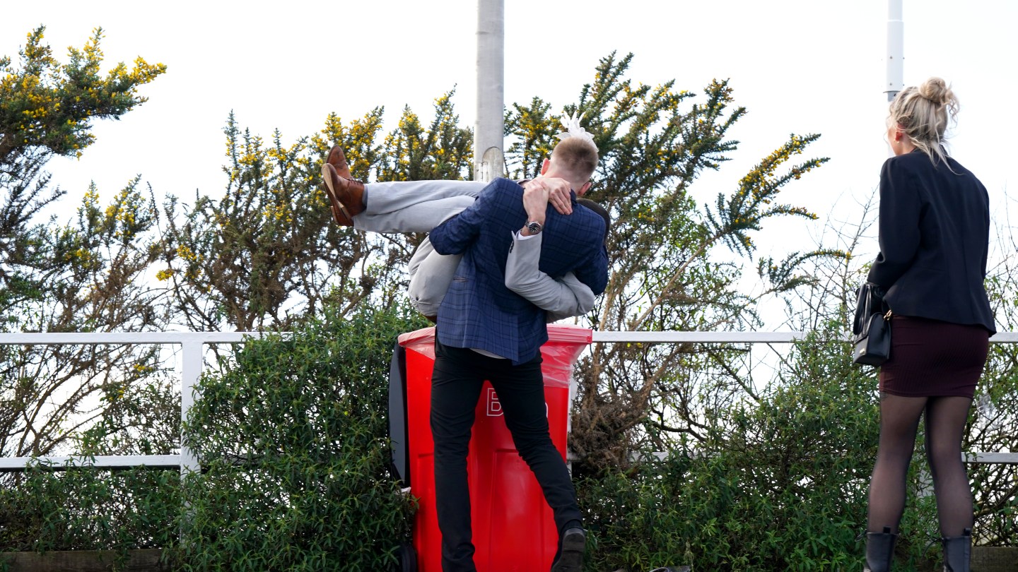 One racegoer places another inside a trashcan at the end of day two of the 2024 Randox Grand National Festival at Aintree Racecourse, Liverpool.