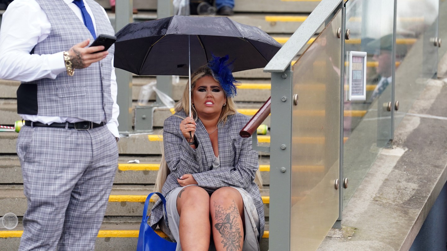 Racegoers take shelter from the rain on day three of the 2024 Randox Grand National Festival at Aintree Racecourse, Liverpool.