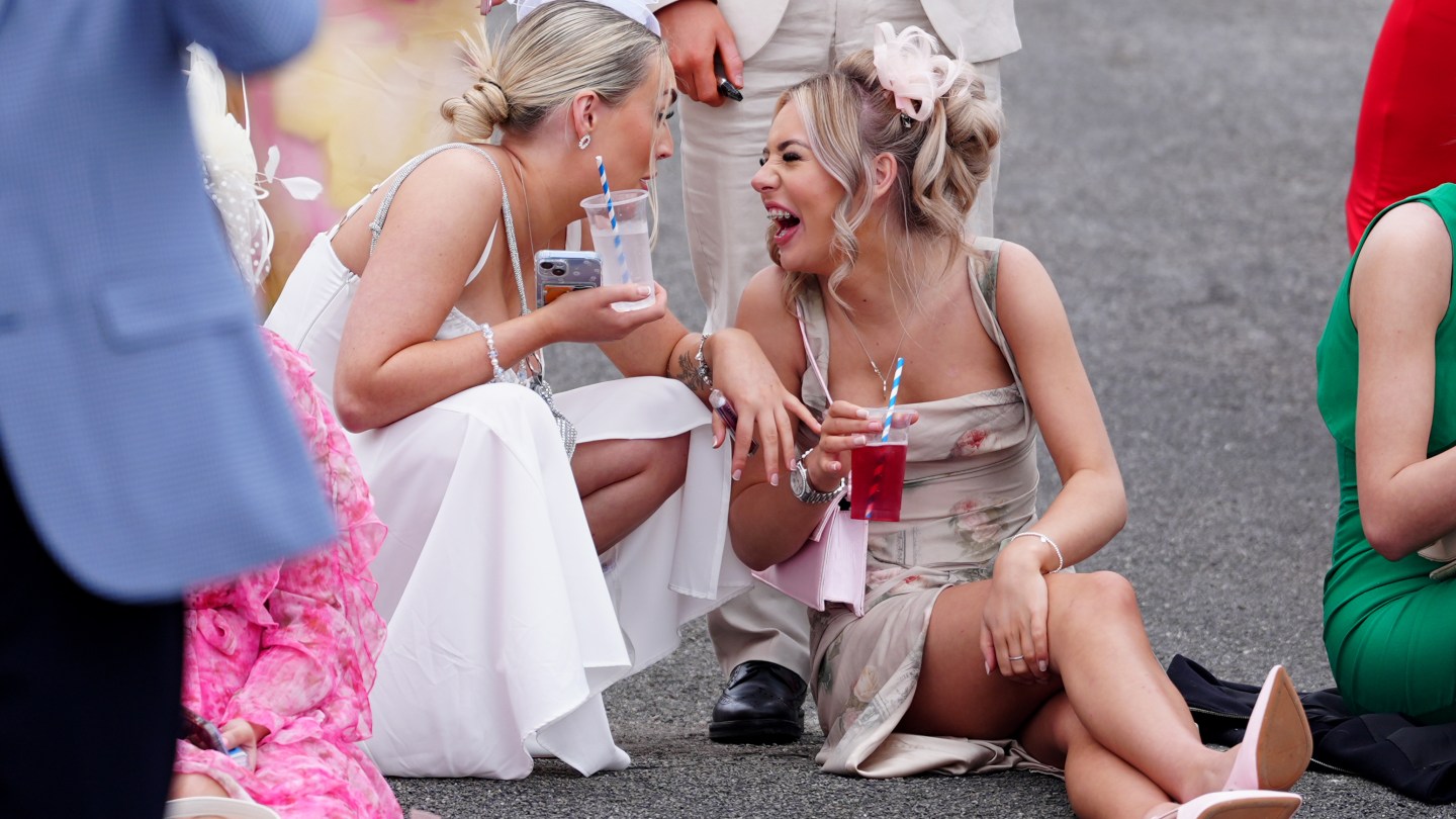 Racegoers laughing together on day two of the 2024 Randox Grand National Festival at Aintree Racecourse, Liverpool.