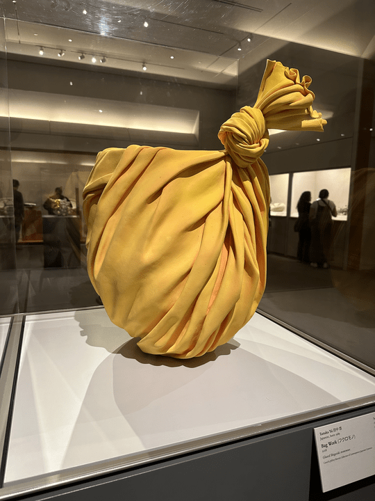 photo of a sculpture of a yellow pot appearing to be wrapped in fabric