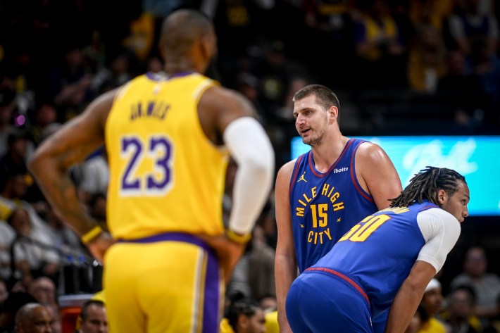 Nikola Jokic (15) of the Denver Nuggets speaks to a referee as LeBron James (23) of the Los Angeles Lakers looms during the first quarter on Tuesday, October 24, 2023.