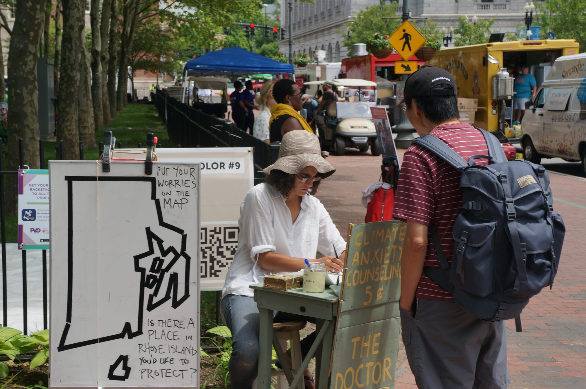 Kate Schapira sits at her climate anxiety booth in a public park in Providence, Rhode Island