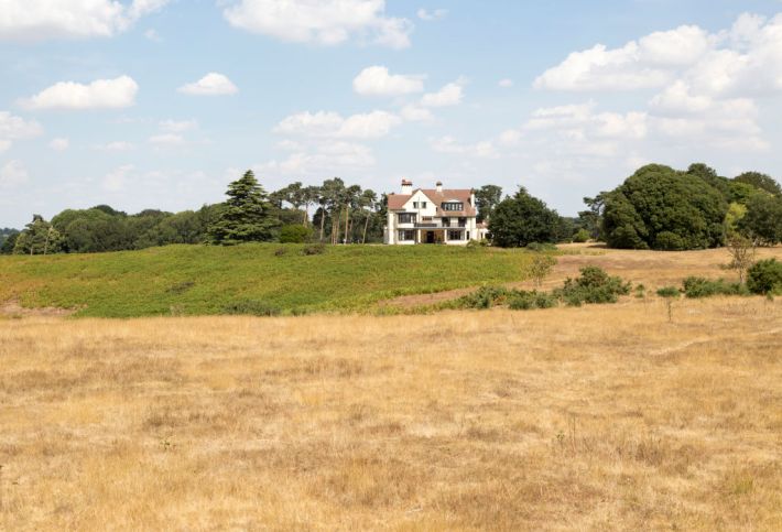 a white country house overlooking green and gold fields