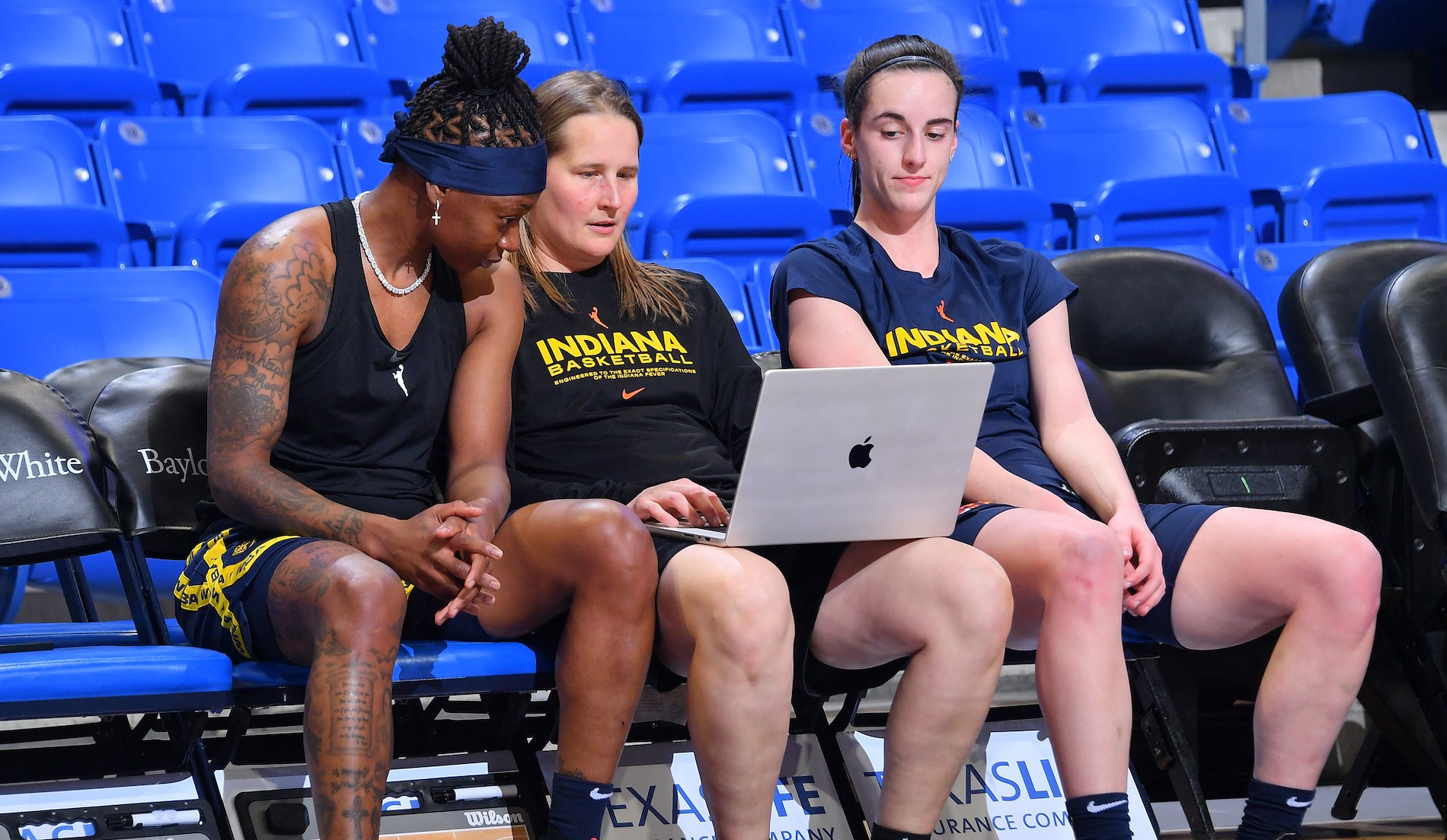 Caitlin Clark #22, Erica Wheeler #17, and Assistant Coach Jessie Miller of the Indiana Fever look on before the game against the Dallas Wings