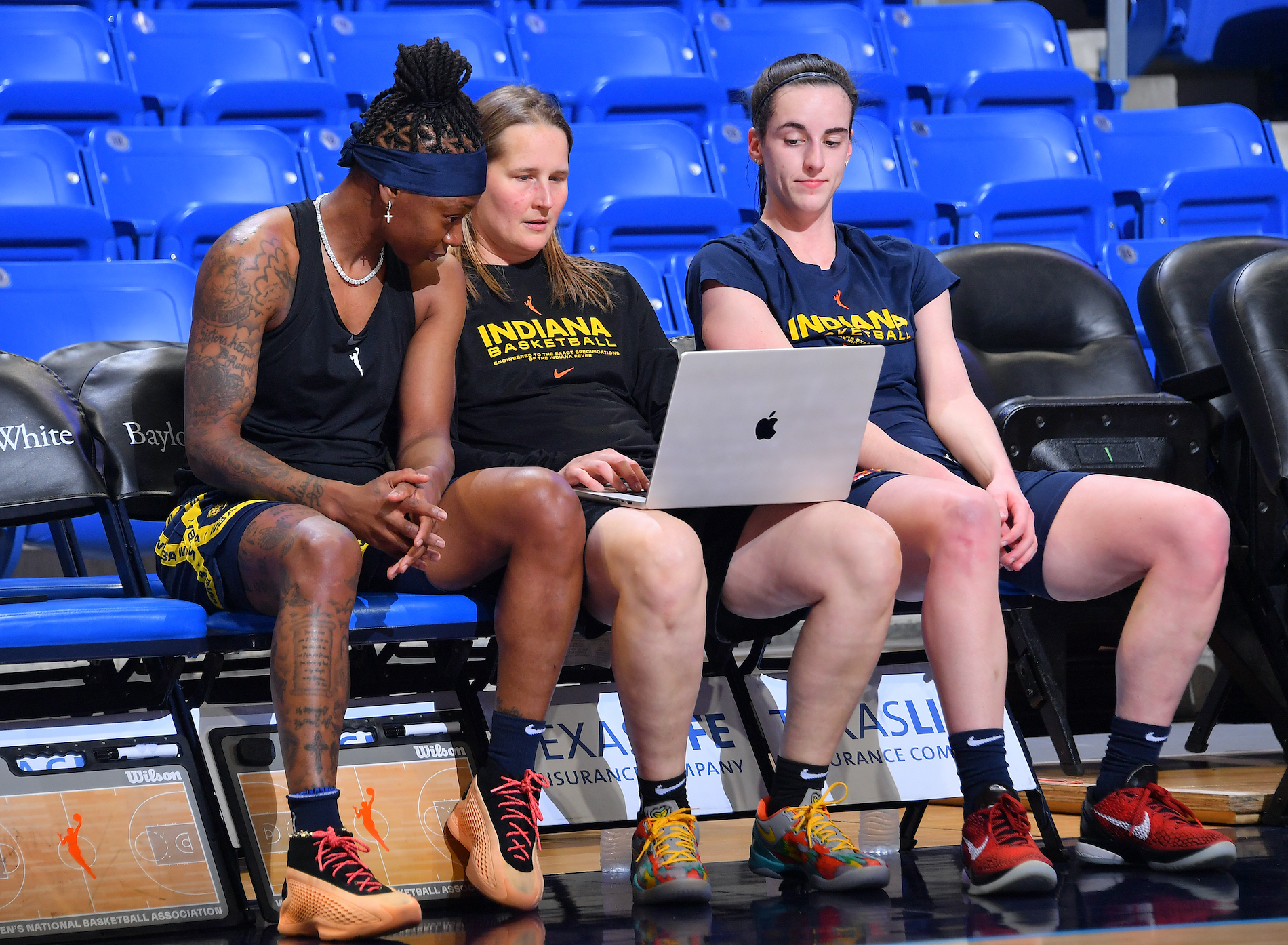 Caitlin Clark #22, Erica Wheeler #17, and Assistant Coach Jessie Miller of the Indiana Fever look on before the game against the Dallas Wings