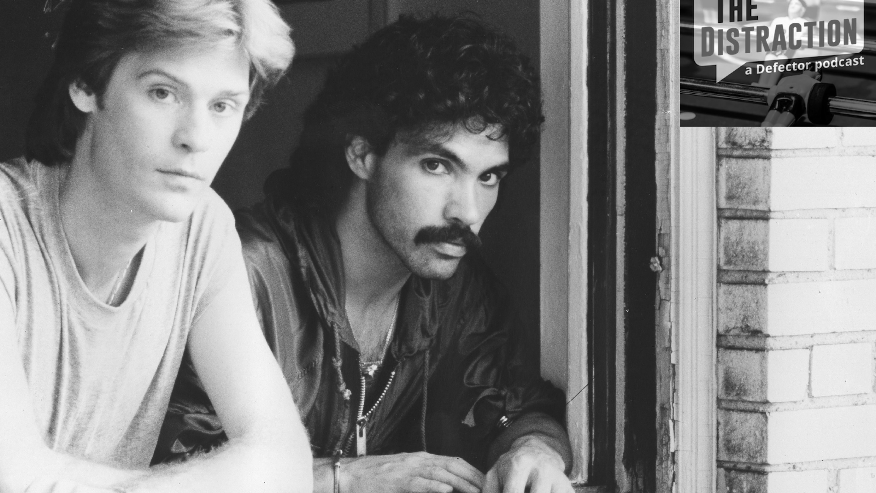 A black-and-white 1970 photograph of Hall & Oates looking out the window of an apartment building, taken by Michael Ochs. The Distraction logo is at upper right.