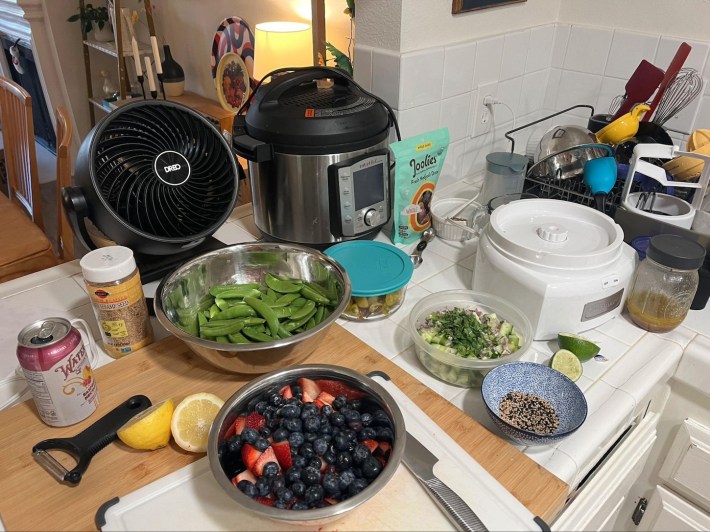 A countertop with several bowls of ingredients, cutting boards, a Y-zester and halved lemon, a knife, and various other kitchen implements.