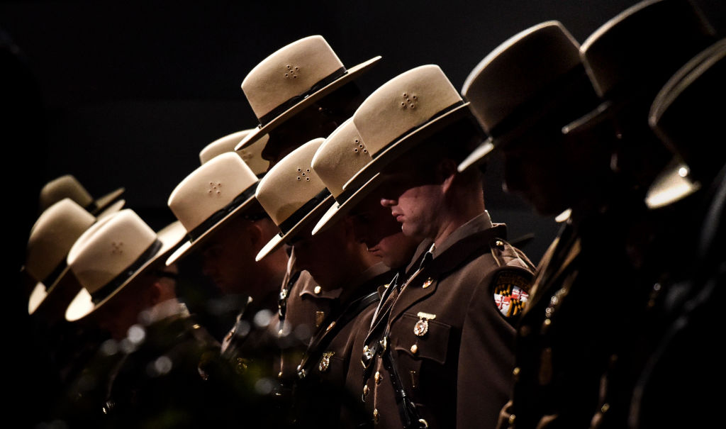 Maryland State Police troopers bowing their heads on stage during a graduation ceremony in 2019.