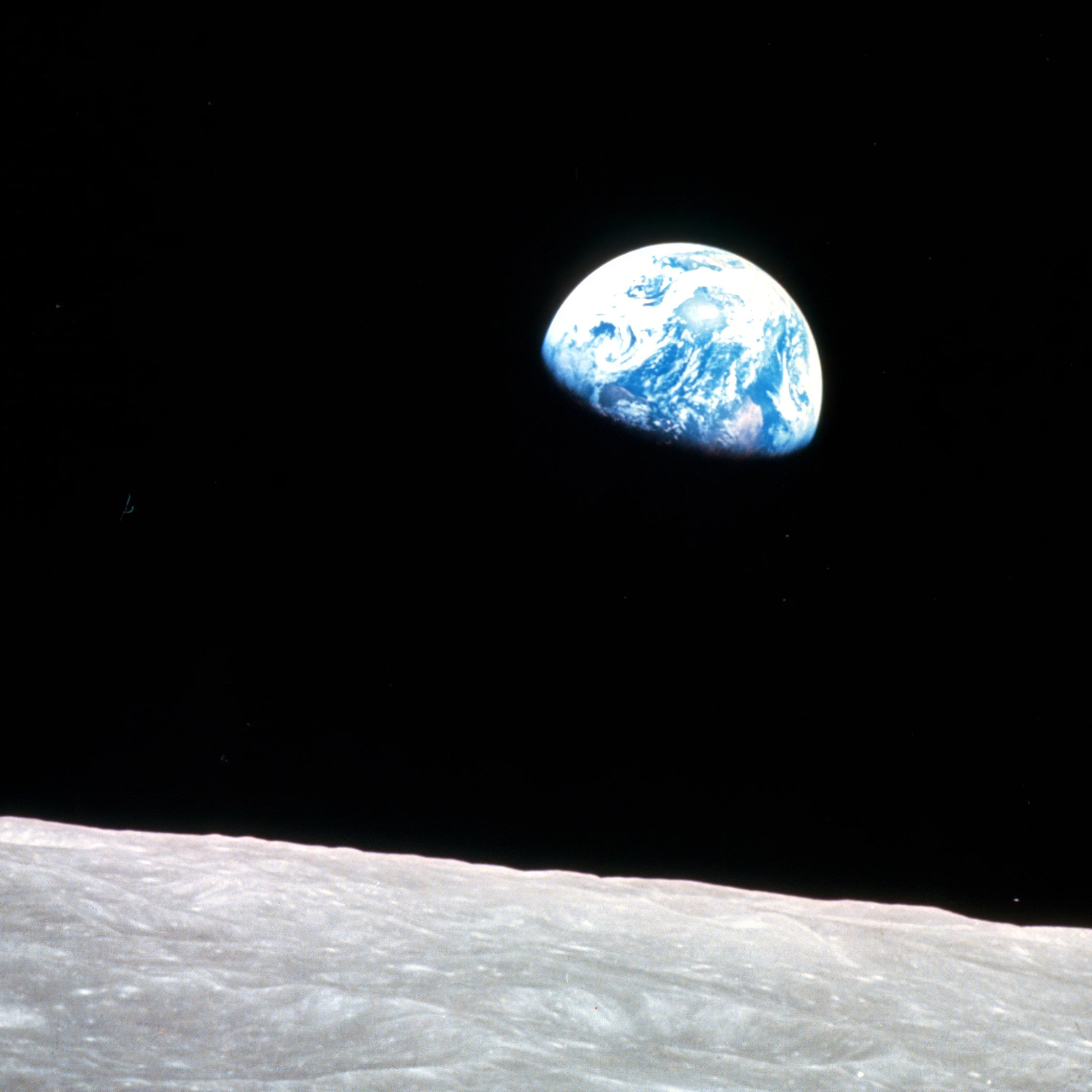 Earthrise - Apollo 8, December 24, 1968. This view of the rising Earth greeted the Apollo 8 astronauts as they came from behind the Moon after the fourth nearside orbit. The photo, by astronaut William Anders, is displayed here in its original orientation, though it is more commonly viewed with the lunar surface at the bottom of the photo. Earth is about five degrees left of the horizon in the photo. The unnamed surface features on the left are near the eastern limb of the Moon as viewed from Earth. The lunar horizon is approximately 780 kilometers from the spacecraft. Height of the photographed area at the lunar horizon is about 175 kilometers.
