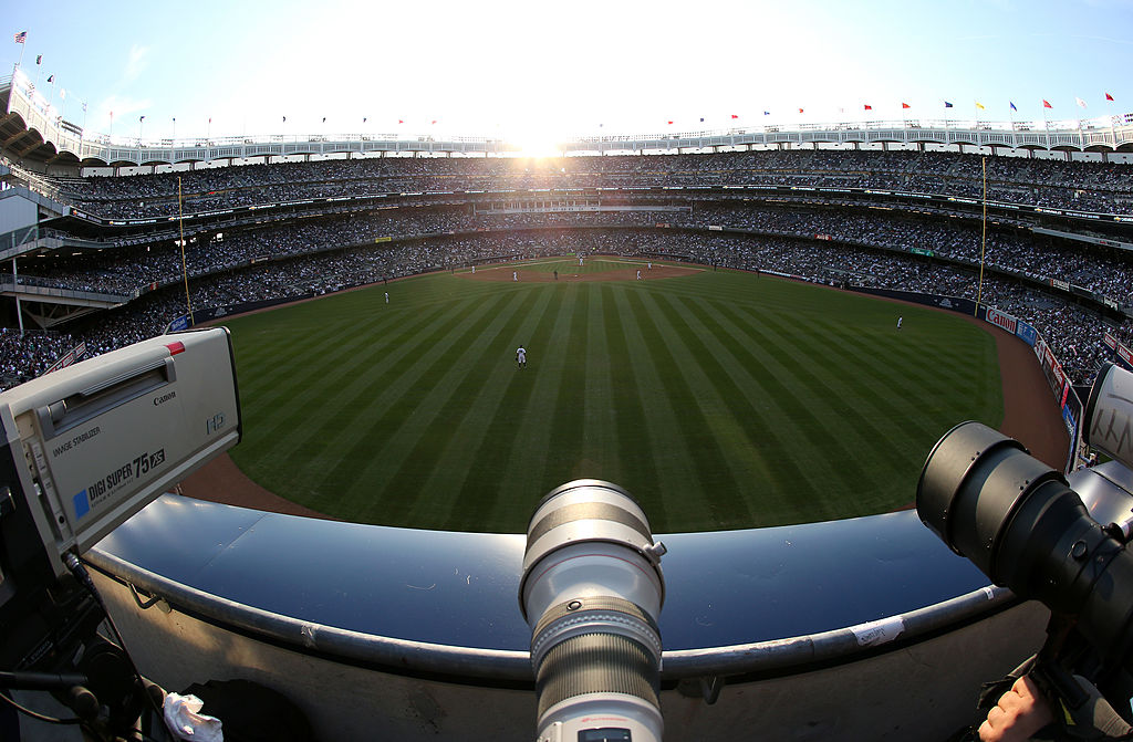 Television video and still camera lenses are seen in centerfield as the sun sets behind home plate