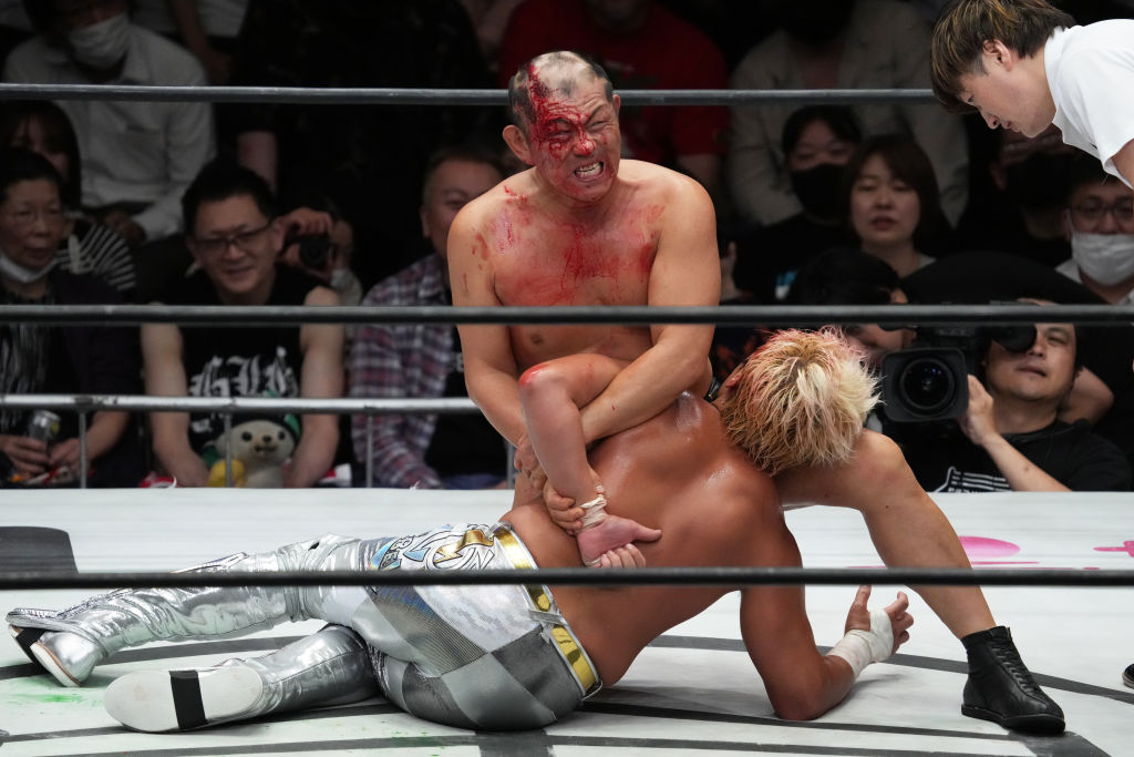 a bloody Minoru Suzuki with Kenoh in a wrestling ring