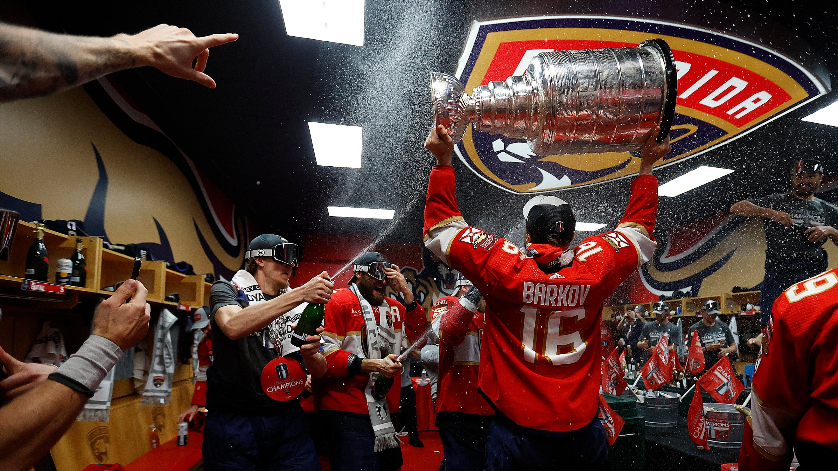 SUNRISE, FLORIDA - JUNE 24: Aleksander Barkov #16 of the Florida Panthers enters the dressing room with the Stanley Cup ready to celebrate with teammates after beating the Edmonton Oilers in Game Seven of the Stanley Cup Final at the Amerant Bank Arena on June 24, 2024 in Sunrise, Florida. (Photo by Eliot J. Schechter/NHLI via Getty Images)