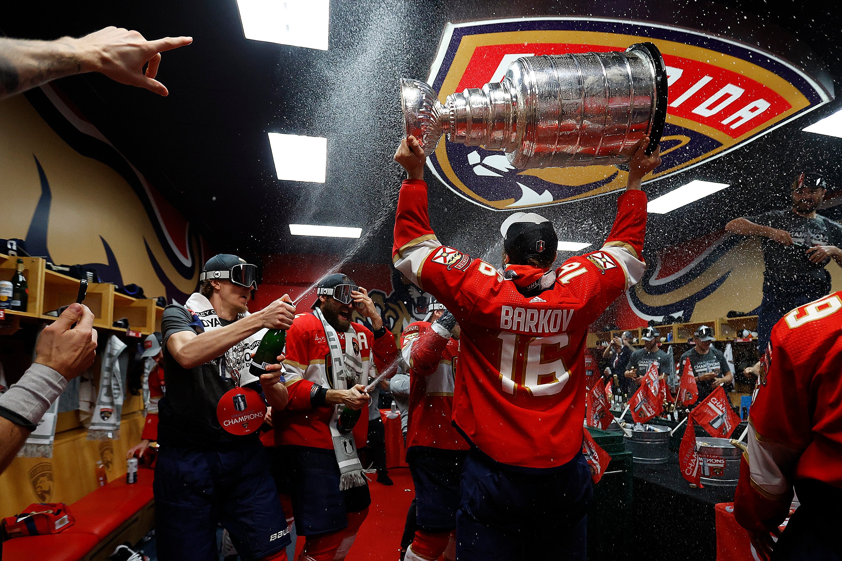 SUNRISE, FLORIDA - JUNE 24: Aleksander Barkov #16 of the Florida Panthers enters the dressing room with the Stanley Cup ready to celebrate with teammates after beating the Edmonton Oilers in Game Seven of the Stanley Cup Final at the Amerant Bank Arena on June 24, 2024 in Sunrise, Florida. (Photo by Eliot J. Schechter/NHLI via Getty Images)