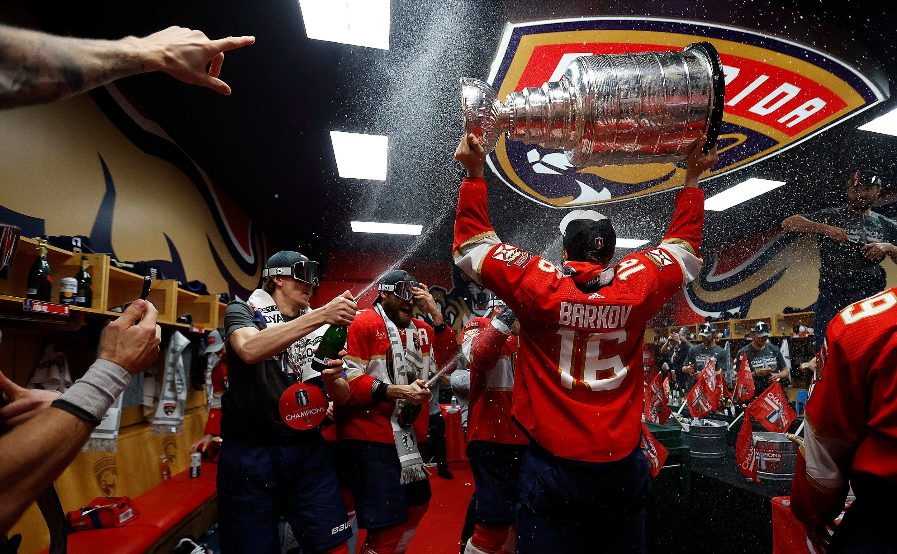 SUNRISE, FLORIDA - JUNE 24: Aleksander Barkov #16 of the Florida Panthers enters the dressing room with the Stanley Cup ready to celebrate with teammates after beating the Edmonton Oilers in Game Seven of the Stanley Cup Final at the Amerant Bank Arena on June 24, 2024 in Sunrise, Florida. (Photo by Eliot J. Schechter/NHLI via Getty Images)