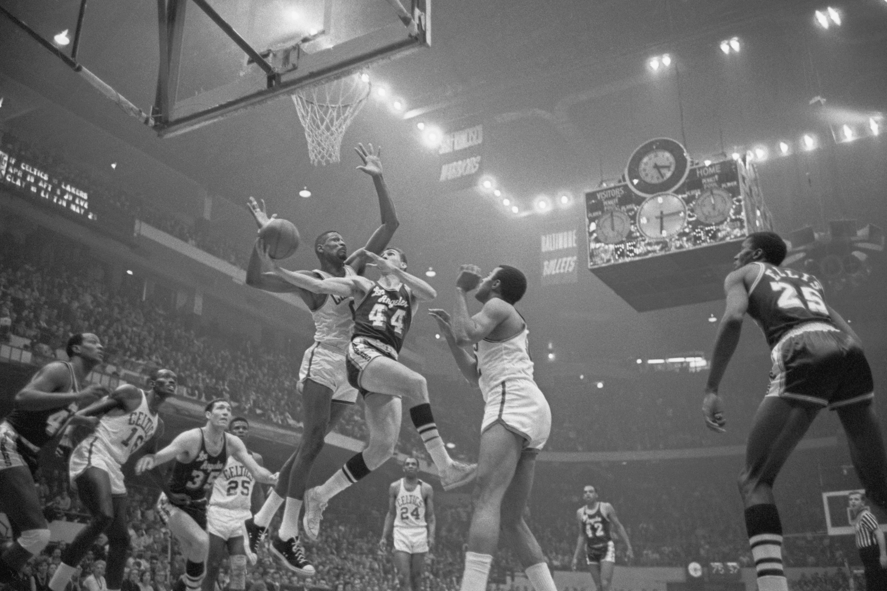 (Original Caption) Lakers' Jerry West (C) is guarded closely by Celtics' Bill Russell (L) as he goes in for a layup, 3rd period, 1st game of championship playoffs of the NBA, Boston Garden (4/18). Celtics' Willie Naulls is on the right. Celtics won the game, 142-110.