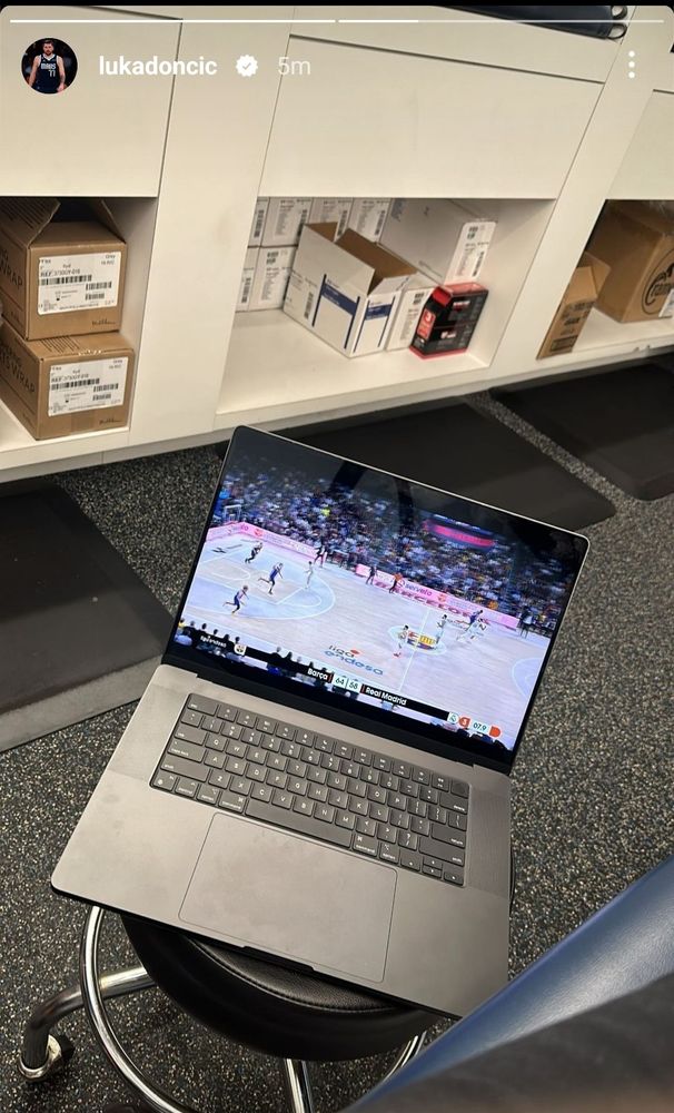 Luka watching a EuroLeague basketball game on a smudgy laptop that's just sitting on a stool in what looks like a training room.