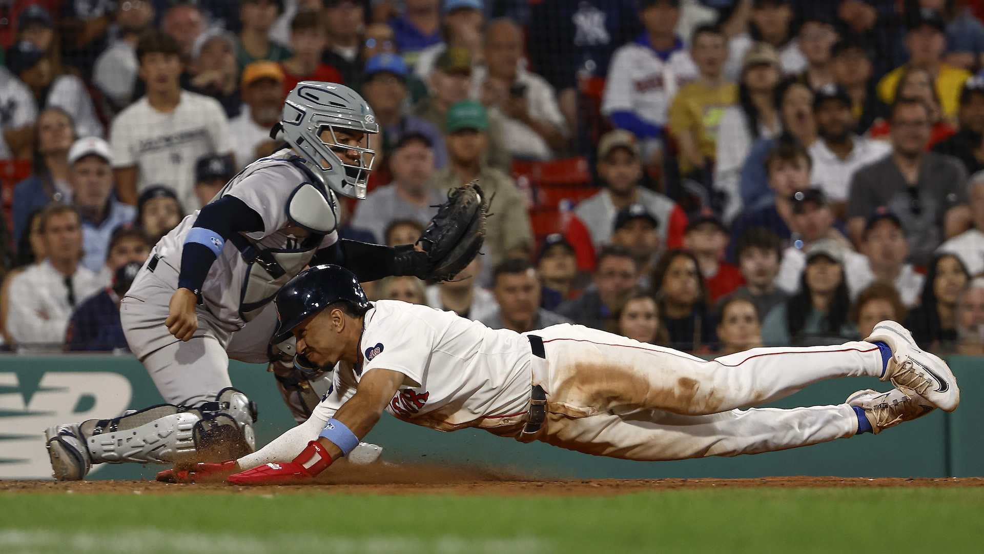 David Hamilton #70 of the Boston Red Sox dives home safely as catcher Jose Trevino #39 of the New York Yankees moves to make a late tag.