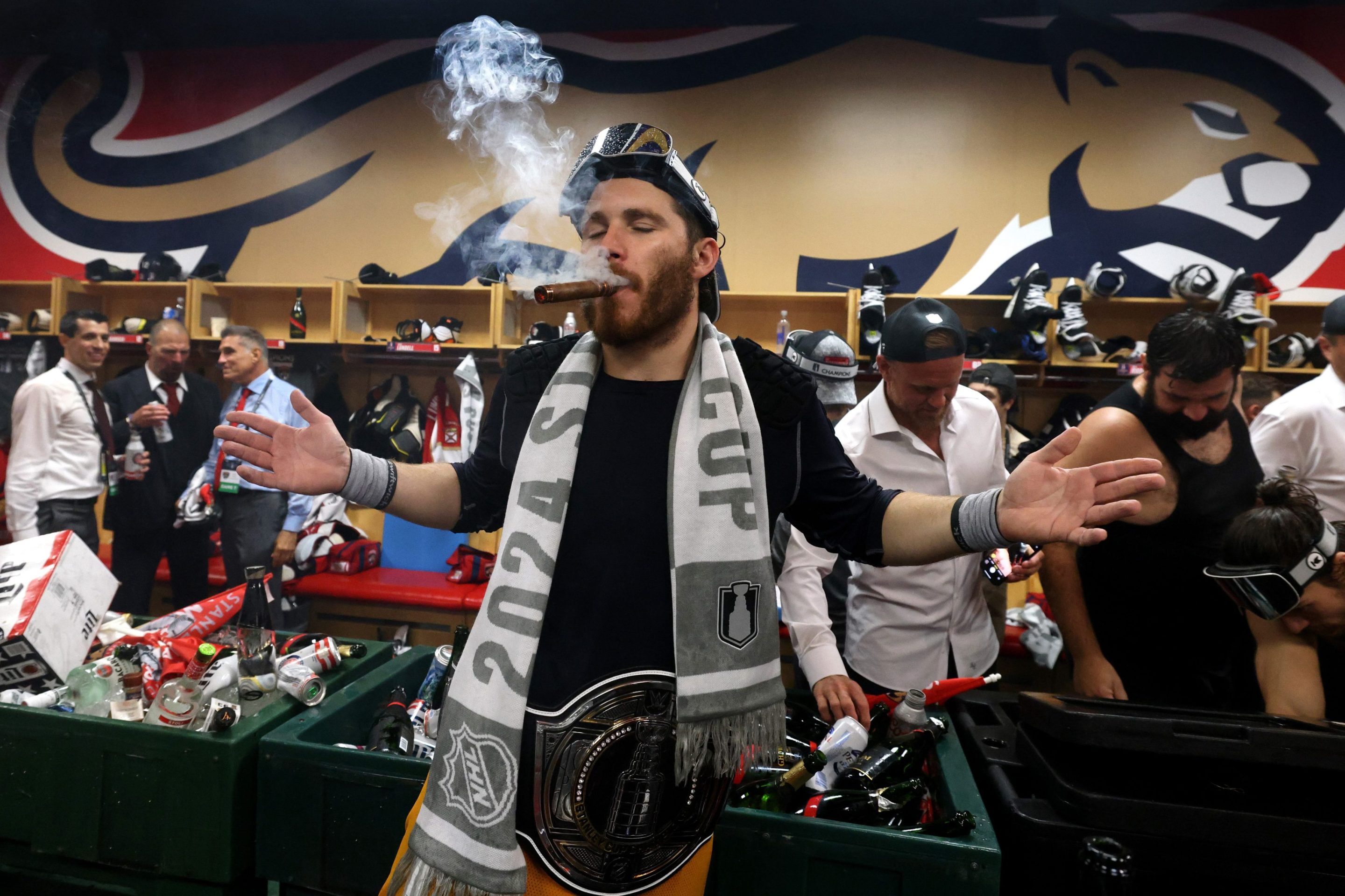 SUNRISE, FLORIDA - JUNE 24: Matthew Tkachuk #19 of the Florida Panthers smokes a cigar while wearing the NHL/WWE Stanley Cup Championship belt in the locker room after Game Seven of the 2024 Stanley Cup Final between the Edmonton Oilers and the Florida Panthers at Amerant Bank Arena on June 24, 2024 in Sunrise, Florida.