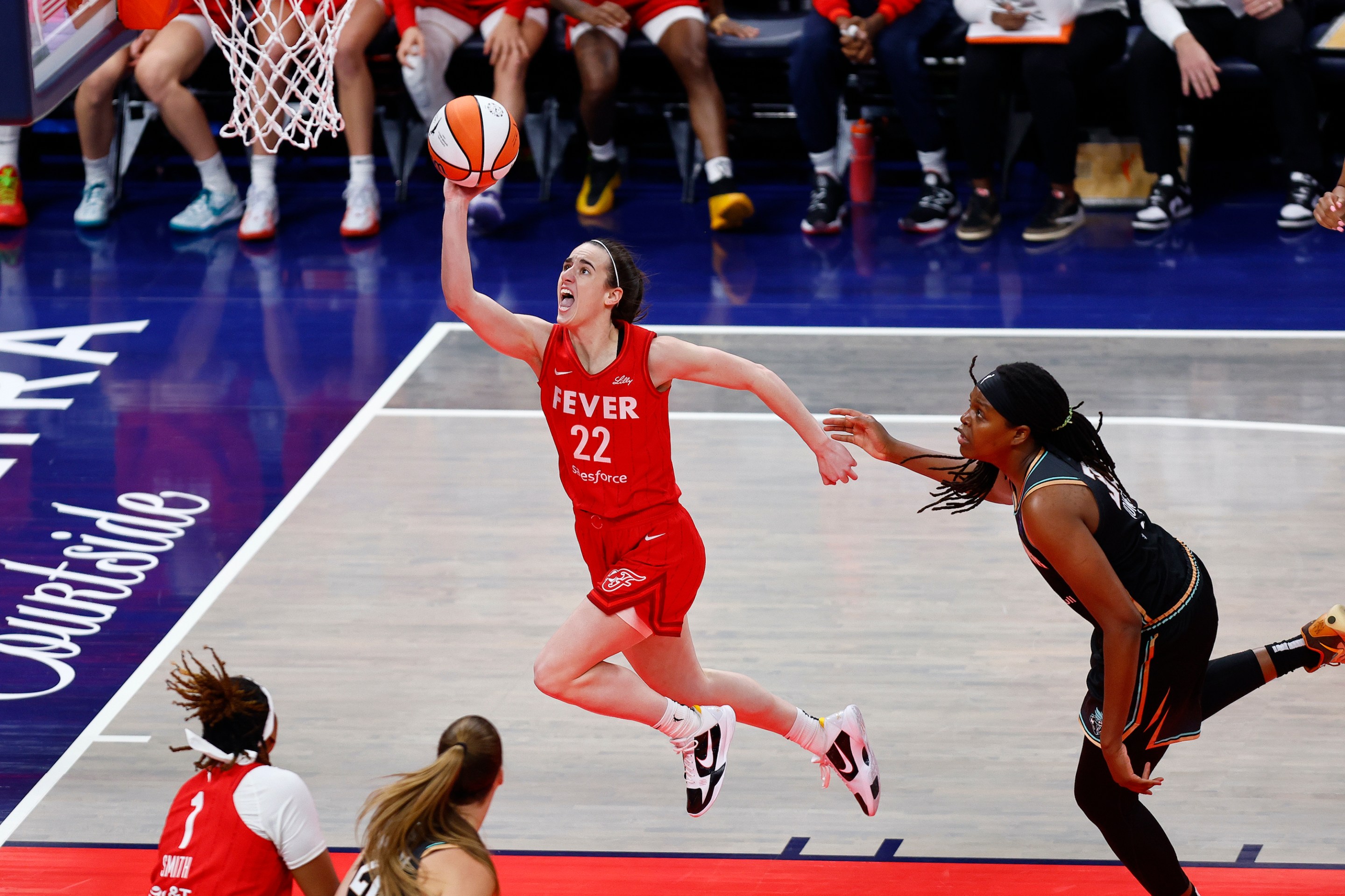 Indiana Fever guard Caitlin Clark (22) drives past New York Liberty forward Jonquel Jones (35) and goes in for two during a WNBA game between the New York Liberty and the Indiana Fever