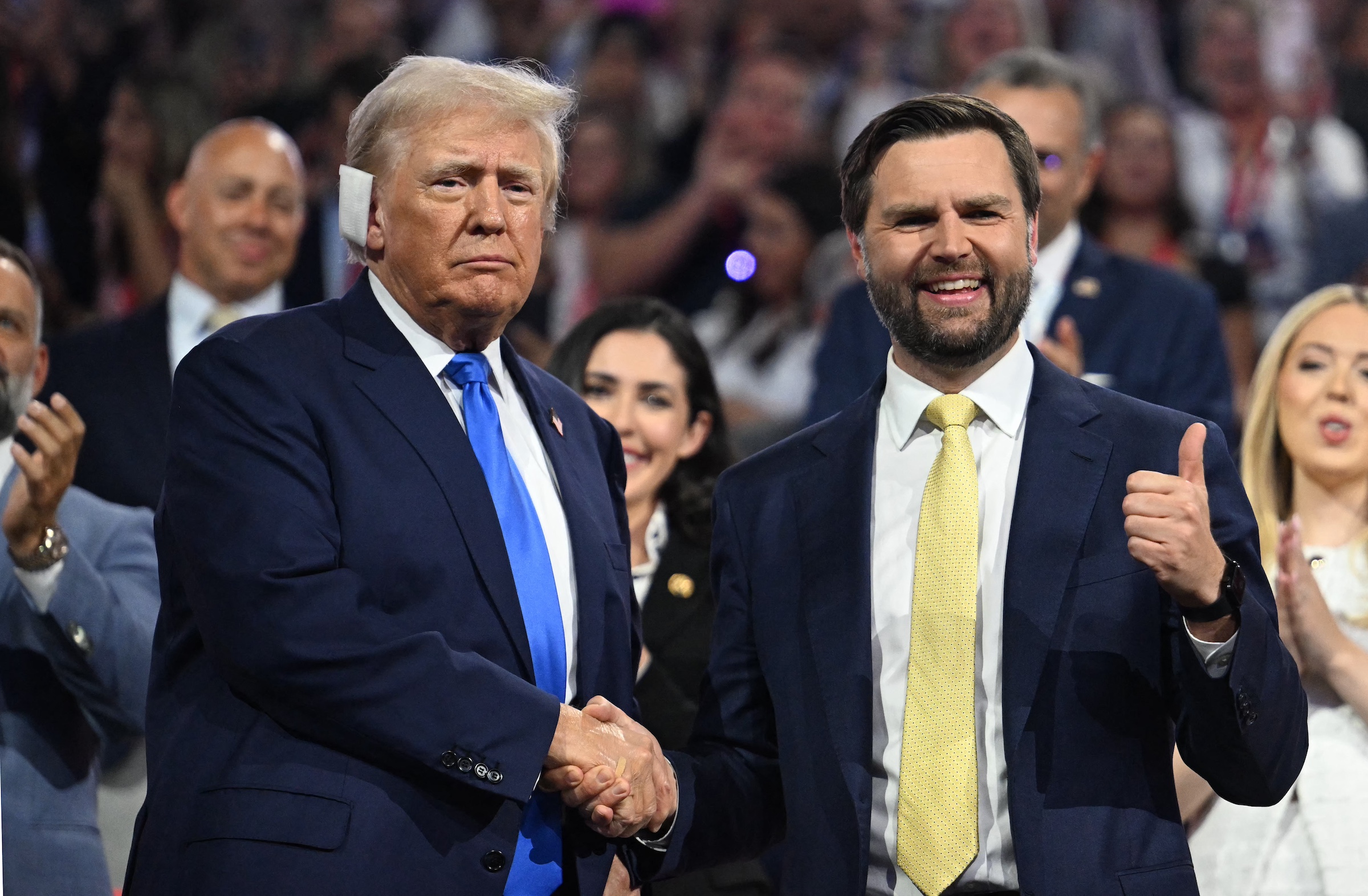 US Senator from Ohio and 2024 Republican vice presidential candidate J.D. Vance (R) gives a thumbs up as he shakes hands with US former President and 2024 Republican presidential candidate Donald Trump during the second day of the 2024 Republican National Convention at the Fiserv Forum in Milwaukee, Wisconsin, July 16, 2024. Days after he survived an assassination attempt Donald Trump won formal nomination as the Republican presidential candidate and picked right-wing loyalist J.D. Vance for running mate, kicking off a triumphalist party convention in the wake of last weekend's failed assassination attempt. (Photo by Jim WATSON / AFP)