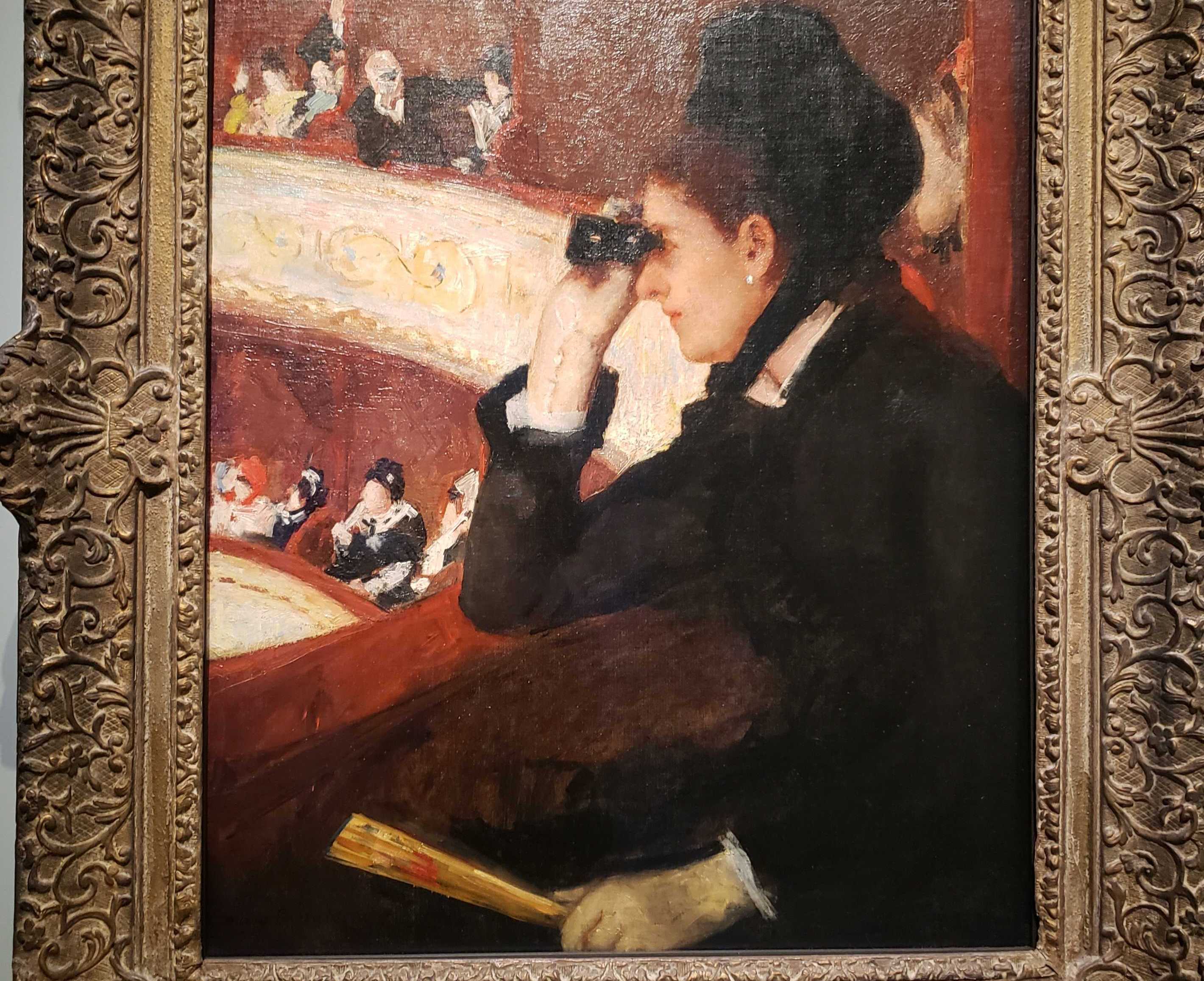 Mary Cassatt's "In The Loge" - a woman in the late 1800s uses opera glasses to look at something from a theater box, while a man looks at her from a distance