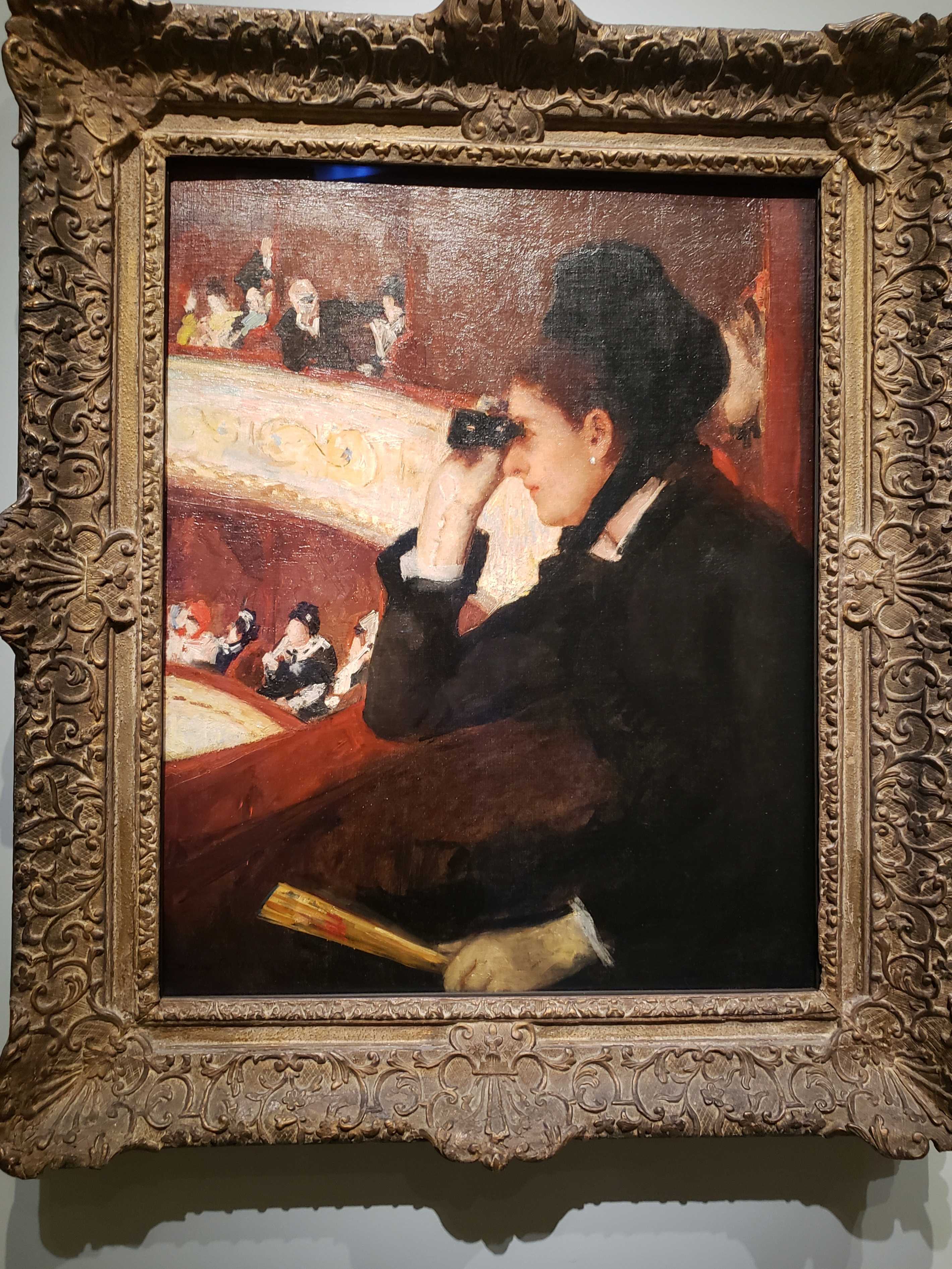 Mary Cassatt's "In The Loge" - a woman in the late 1800s uses opera glasses to look at something from a theater box, while a man looks at her from a distance