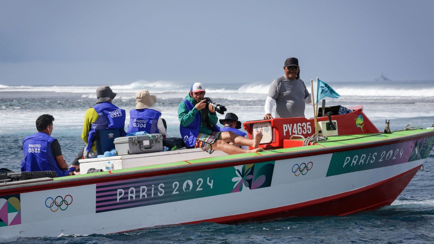 AFP photographer Jerome Brouillet (C) takes photographs from the pool media boat during the the first day of surfing competition at the Paris 2024 Olympic Games, in Teahupo'o on the French Polynesian Island of Tahiti, on July 28, 2024. AFP photographer Jerome Brouillet knew to expect fireworks when he saw Brazilian Olympic surfer Gabriel Medina paddle into one of the day's biggest waves at one of the world's heaviest surf breaks. What he didn't know was that his picture of Medina kicking out of the wave after a ride that earned a record Olympics score in Tahiti would become a global sensation, and likely a defining image of the sport and the Games.