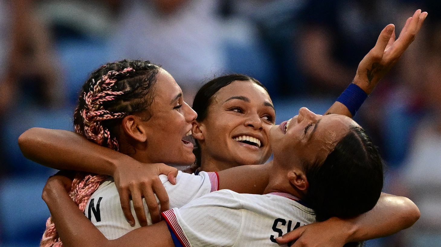 US' forward #05 Trinity Rodman (L) and US' forward #09 Mallory Swanson (R) celebrate after US' forward #11 Sophia Smith (C) scored in the 95th minute during the women's semi-final football match between USA and Germany during the Paris 2024 Olympic Games at the Lyon Stadium in Lyon on August 6, 2024.