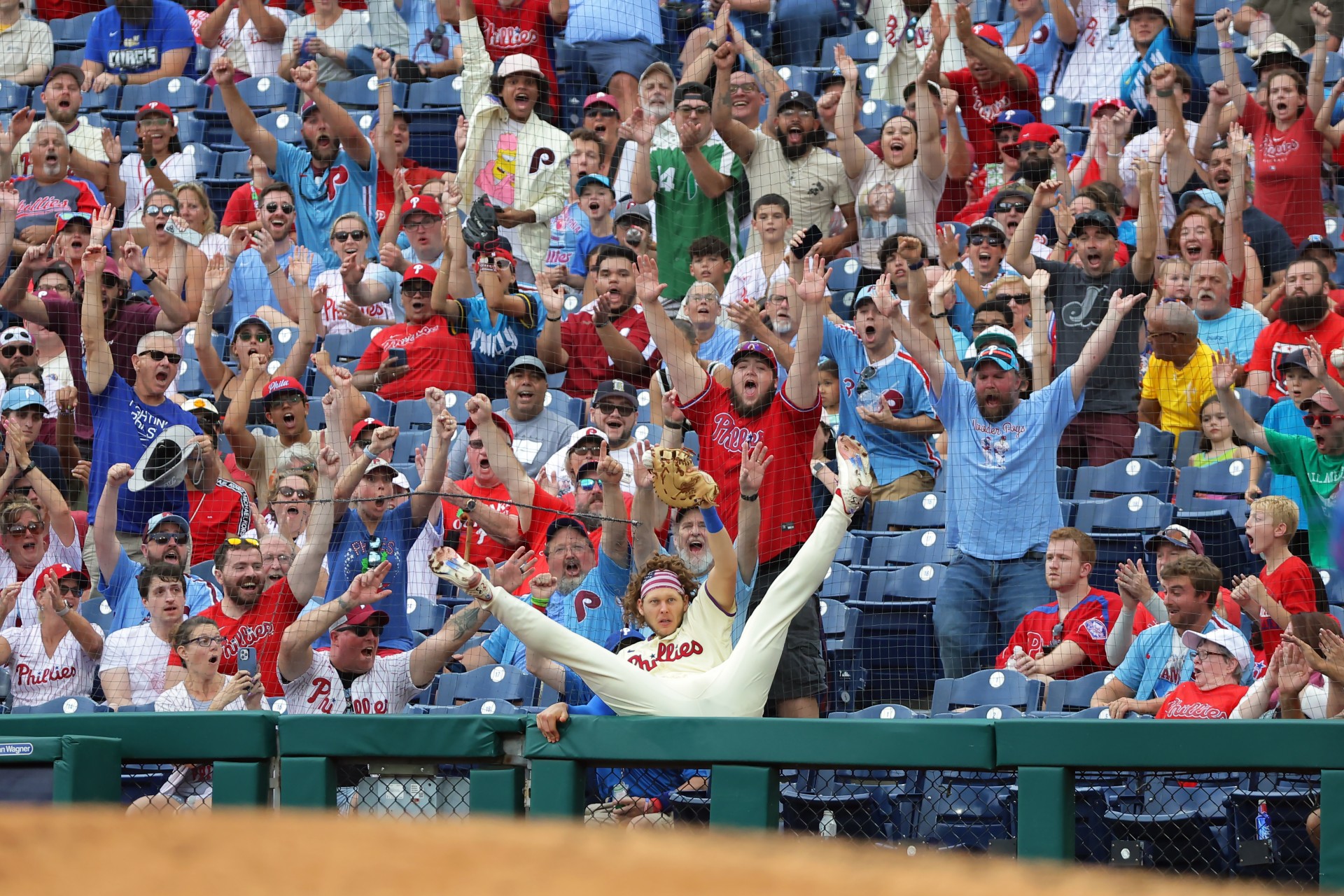 Alec Bohm #28 of the Philadelphia Phillies catches a foul ball as he falls back into the stands in the ninth inning