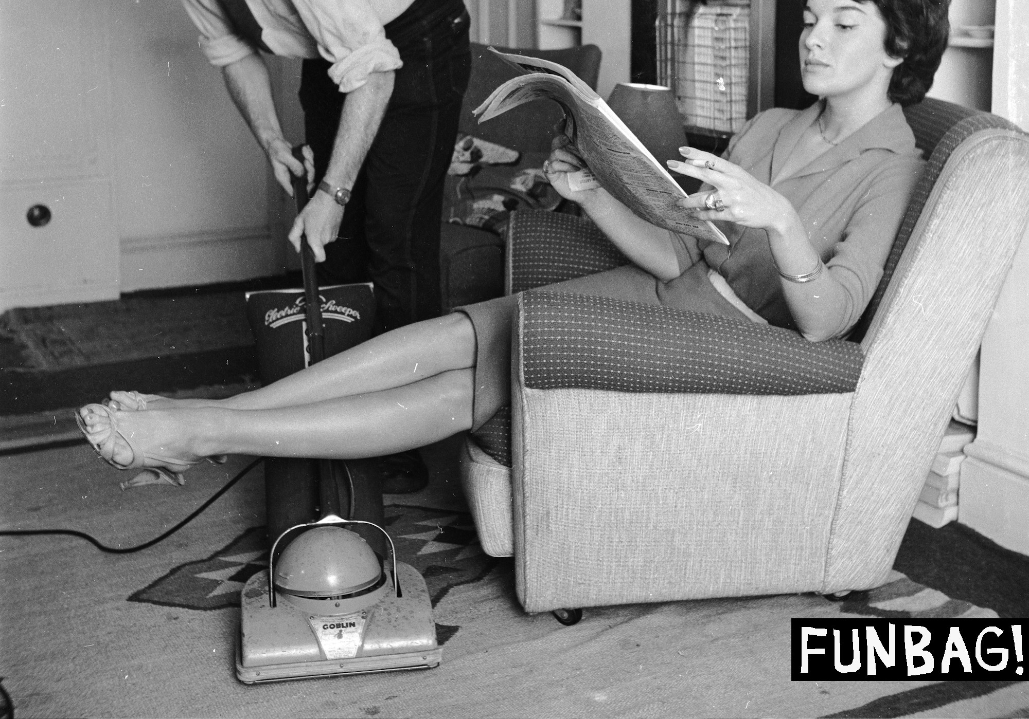 September 1958: An employee of the 'Housewives Help Service' hoovering the living room of a businesswoman while she relaxes. (Photo by Frank Martin/BIPs/Getty Images)