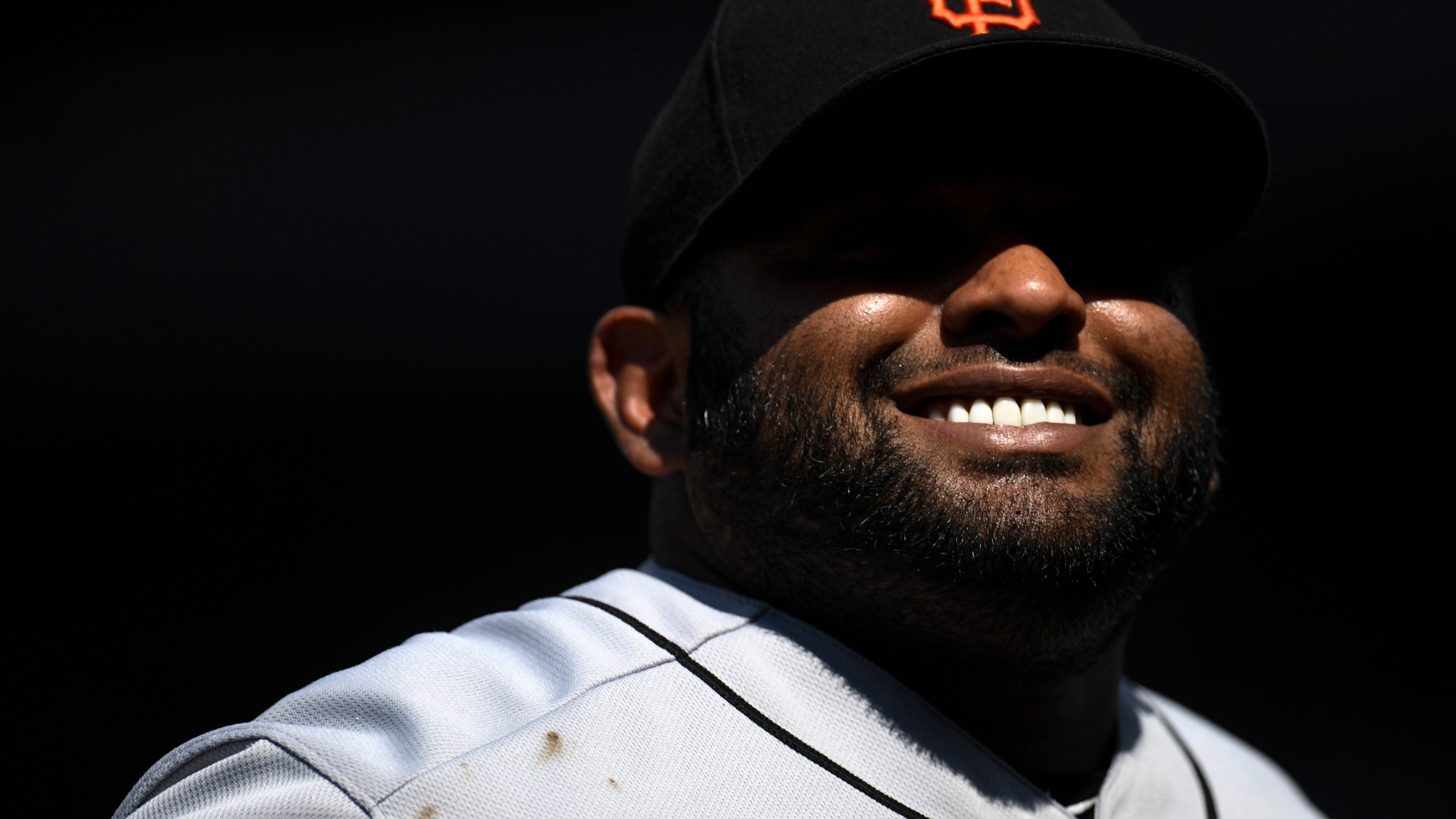 Pablo Sandoval smiling, with the shadow of his hat casting an Oakley Blade-shaped shadow across his eyes, before a San Francisco Giants game in 2019.