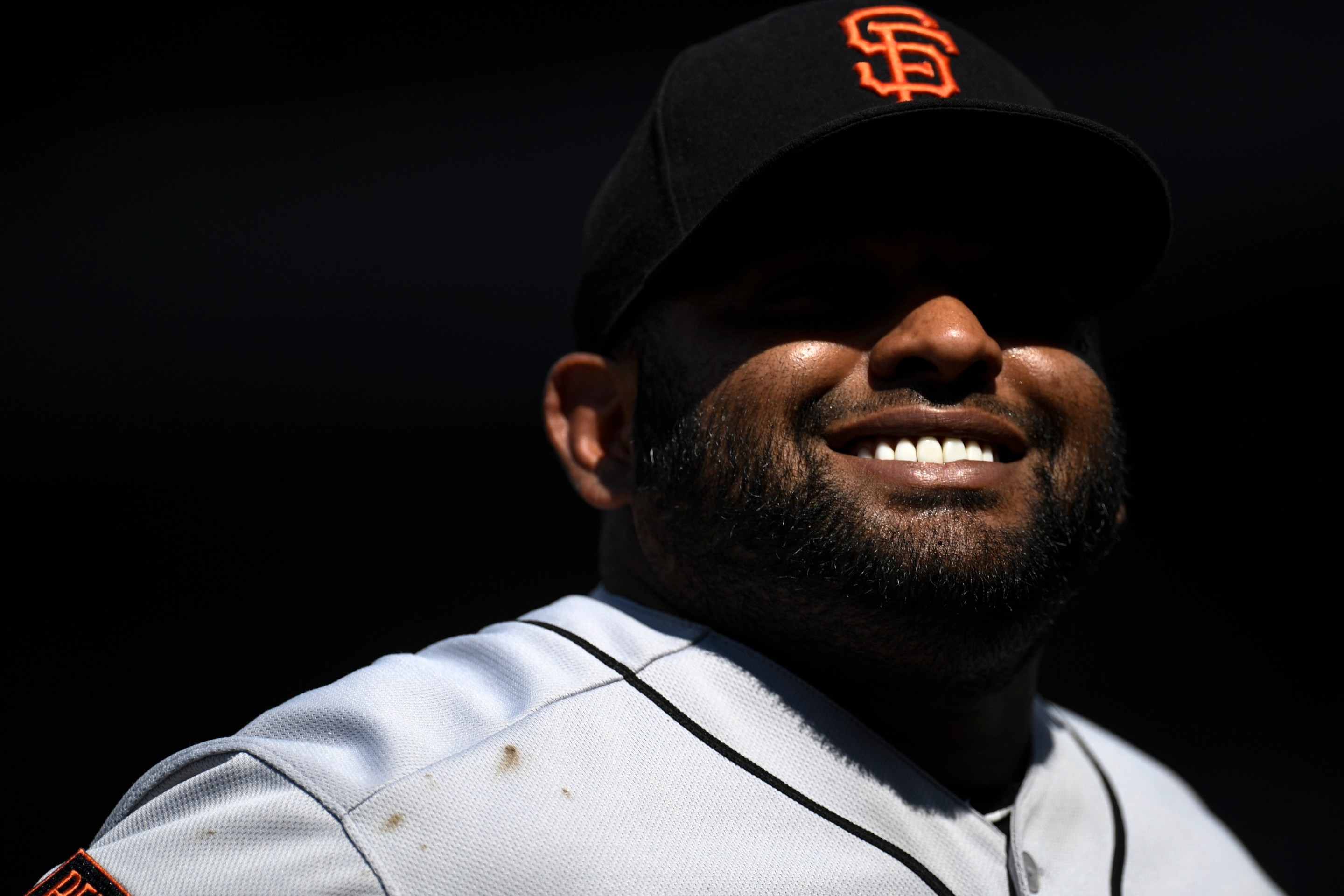 Pablo Sandoval smiling, with the shadow of his hat casting an Oakley Blade-shaped shadow across his eyes, before a San Francisco Giants game in 2019.