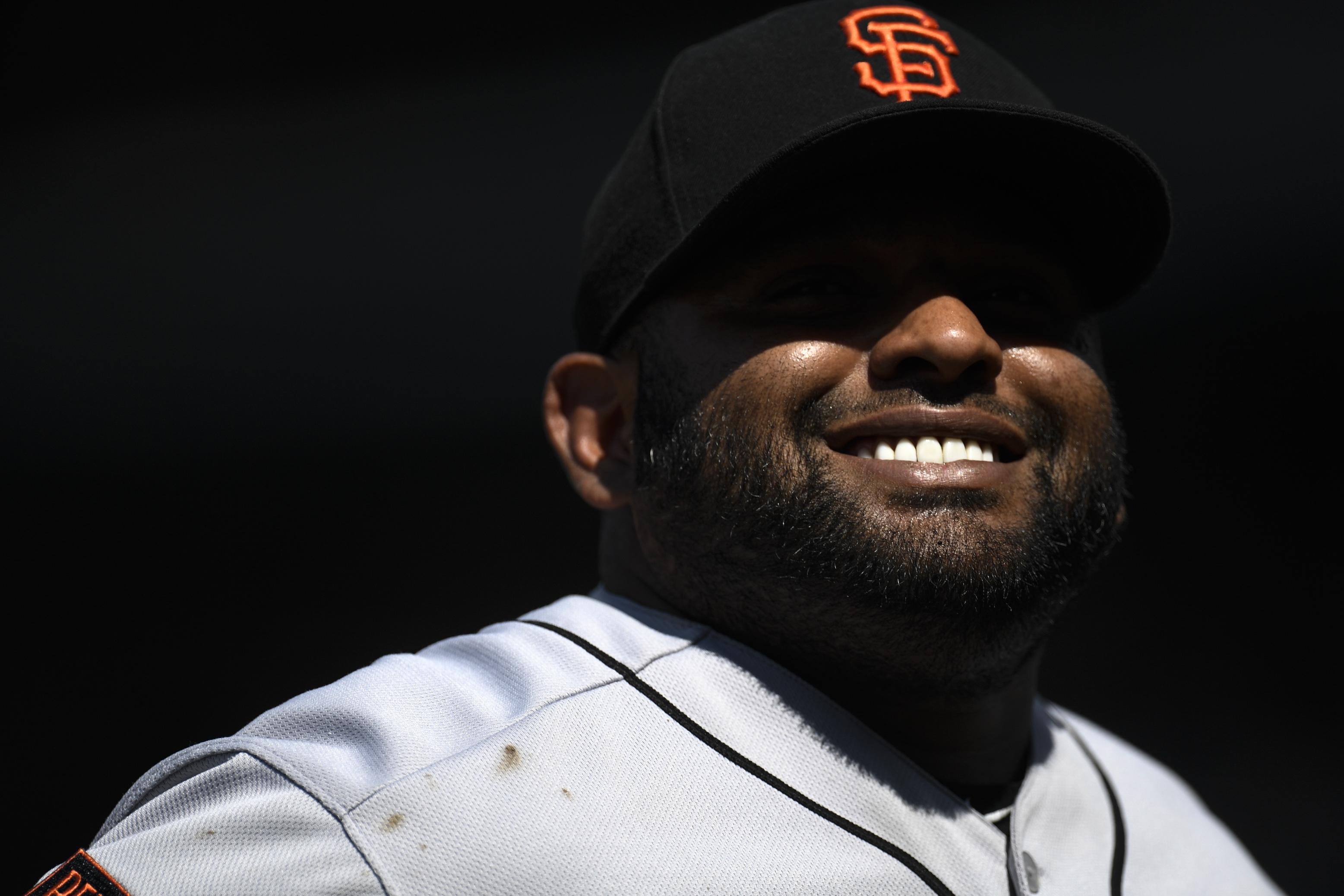 Pablo Sandoval smiling, with the shadow of his hat casting an Oakley Blade-shaped shadow across his eyes, before a San Francisco Giants game in 2019.