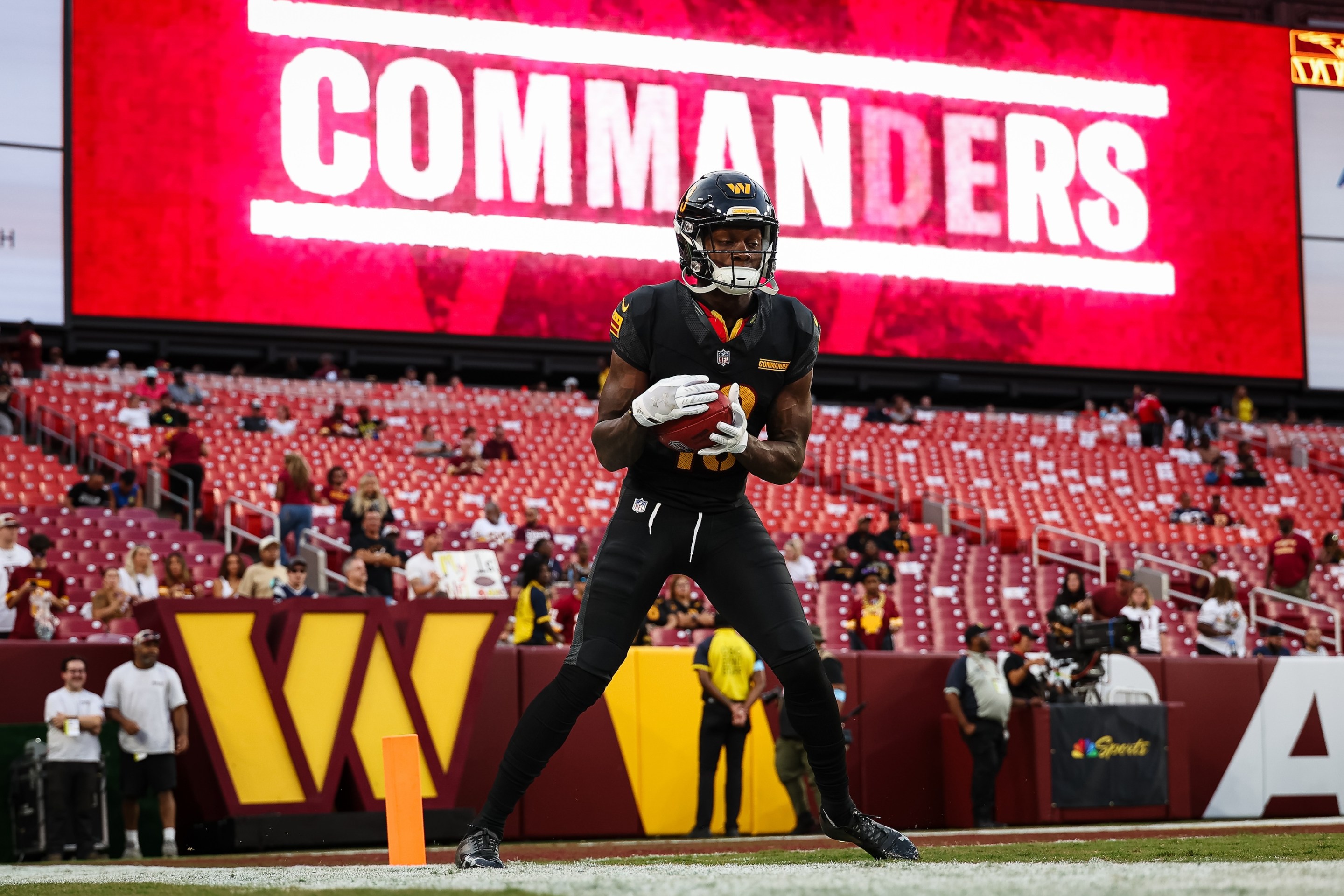 Byron Pringle of the Washington Commanders warms up in front of a big screen with the word COMMANDERS on it, before a Commanders preseason game in August of 2024.