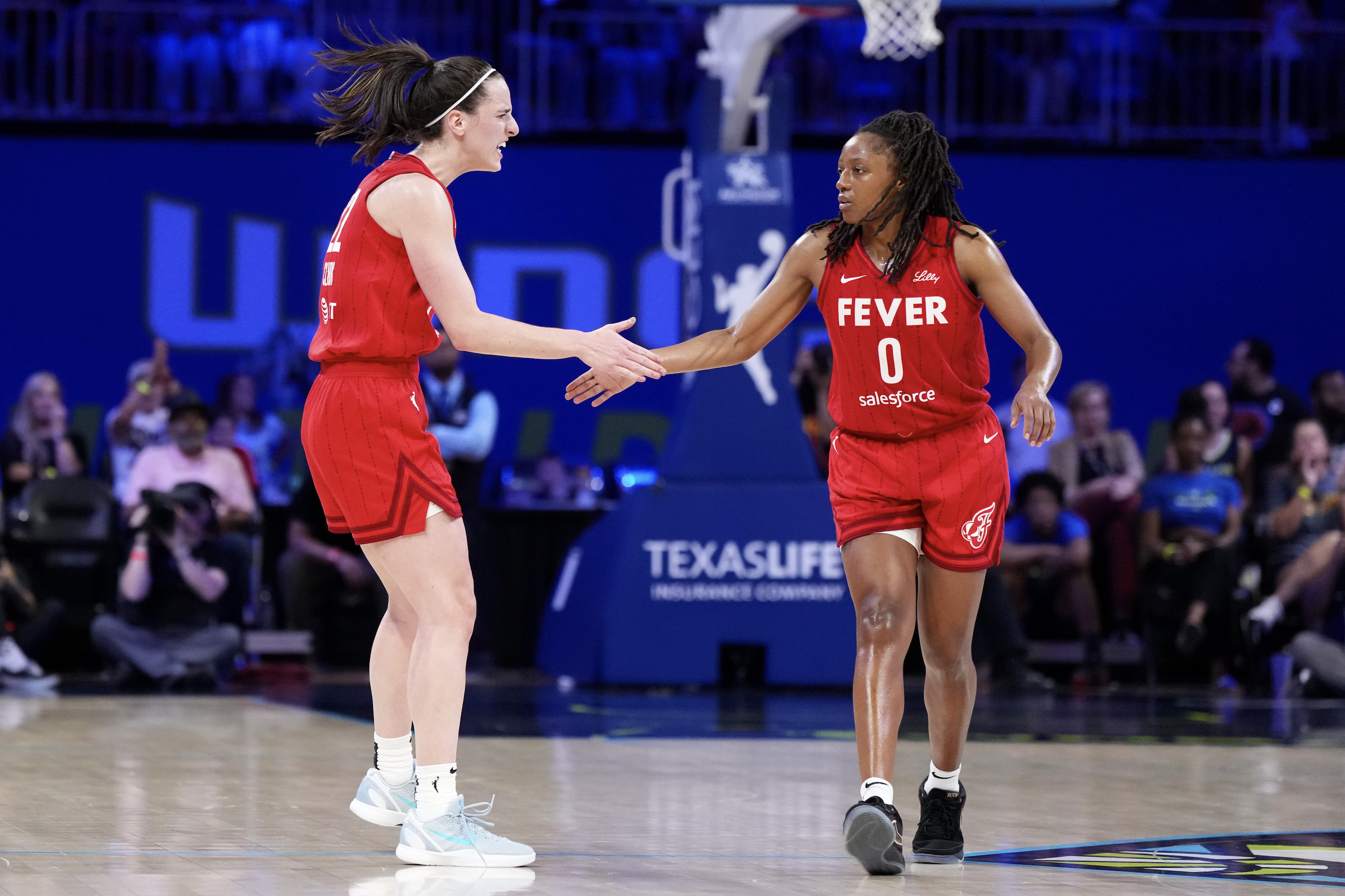 Kelsey Mitchell #0 of the Indiana Fever is congratulated by Caitlin Clark #22 after scoring during the second half against the Dallas Wings at College Park Center on September 01, 2024 in Arlington, Texas.