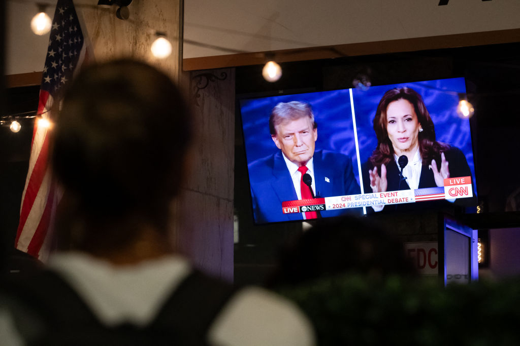 A person stops to watch a TV screen at a bar in Washington D.C. showing the U.S. presidential debate between Vice President Kamala Harris and former President Donald Trump.