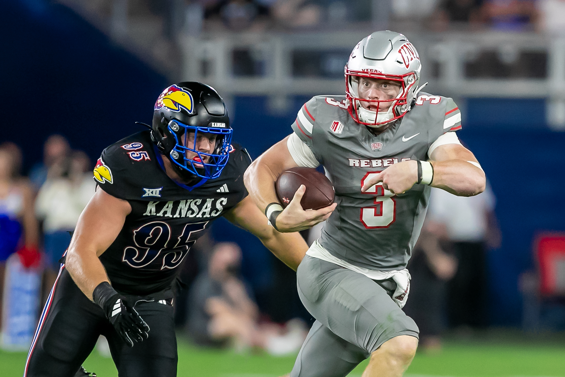 UNLV quarterback Matthew Sluka (3) scrambles with the ball past Kansas defensive end Dylan Wudke (95) during the game between the Kansas Jayhawks and the UNLV Rebels on Friday September 13, 2024 at Children's Mercy Park in Kansas City, Kansas.