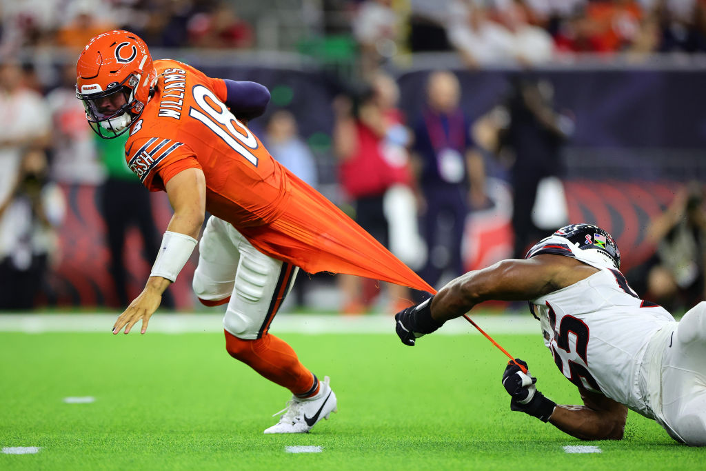 Caleb Williams gets his jersey tugged while avoiding a sack