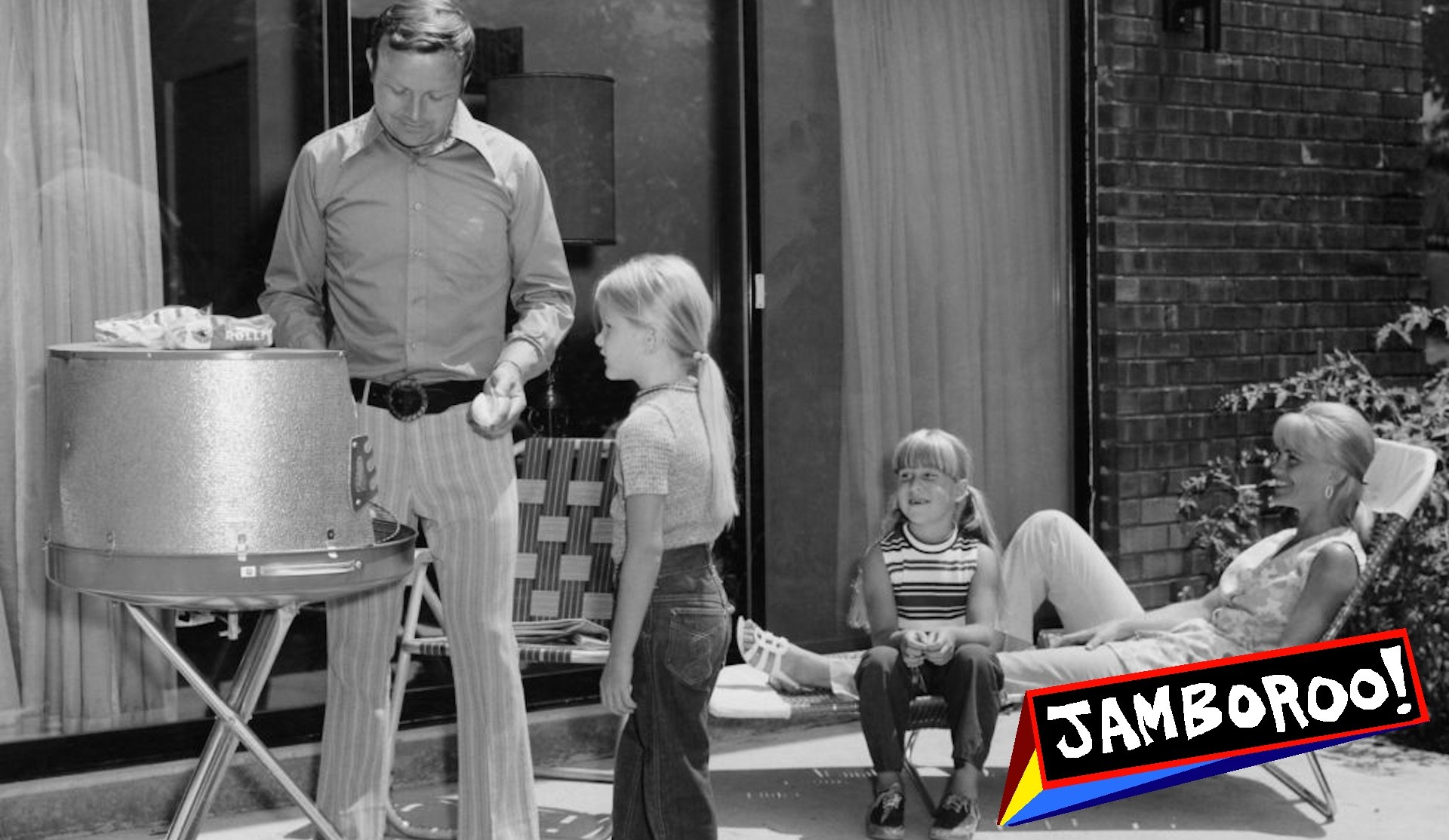 Father cooking on barbecue with wife and daughters