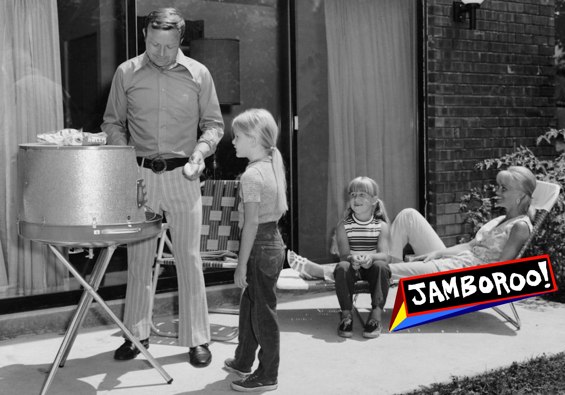 Father cooking on barbecue with wife and daughters