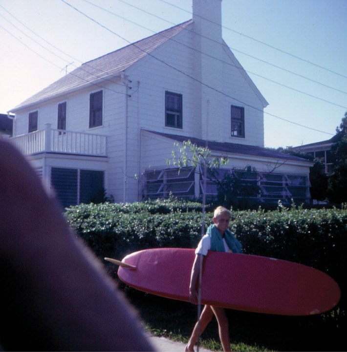 A young surfer carries his board