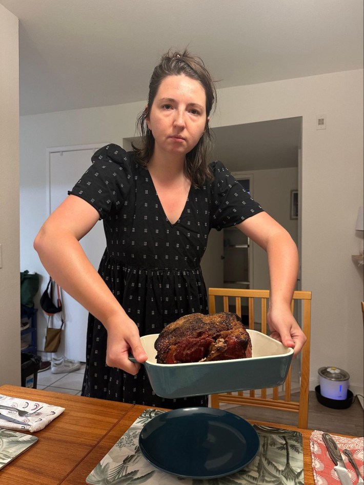 Libby Watson holding a roasting pan with a big roasted hunk of pork in it.