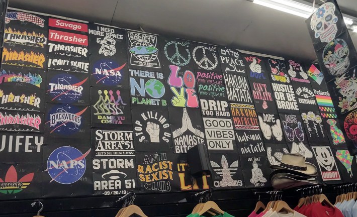 A wall of t-shirts at a t-shirt place on the Wildwood boardwalk. There are Black Lives Matter shirts, and one reading Anti Racist Sexist Club, but also like 15 different Thrasher shirts, four that involve the phrase Hakuna Matata, and a speaker blocking one that says Namaste Bitch.